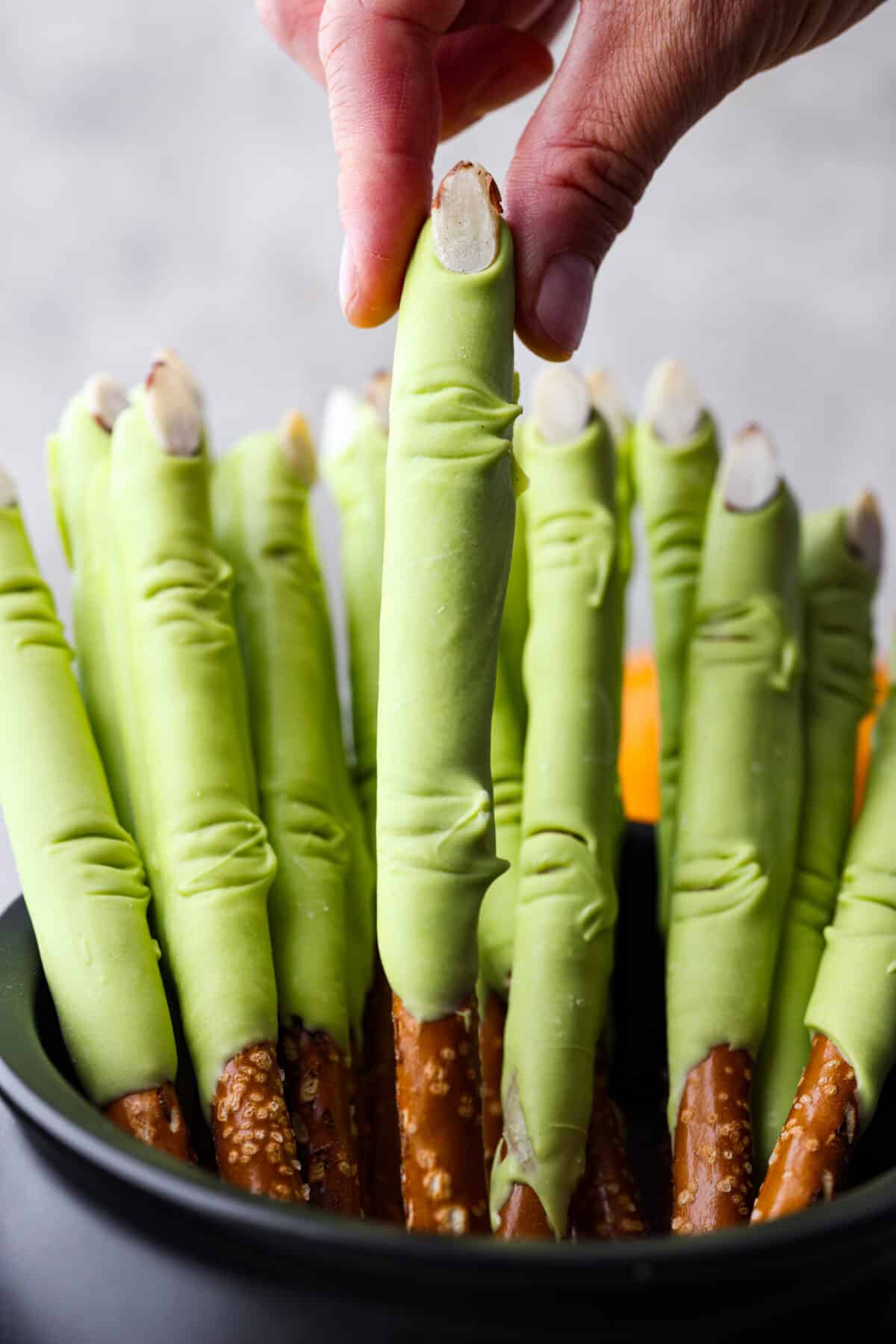 A close up of witch fingers in a cauldron and a hand pulling one of them out 