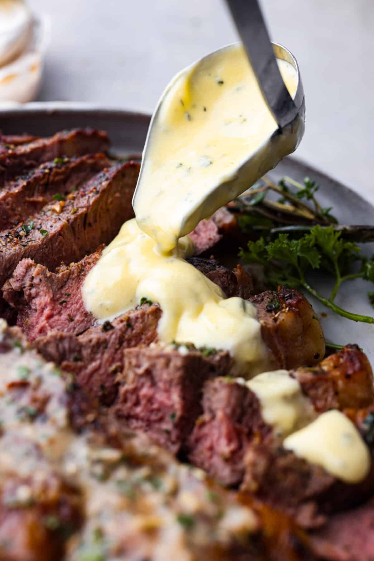 Pouring sauce over sliced steak.