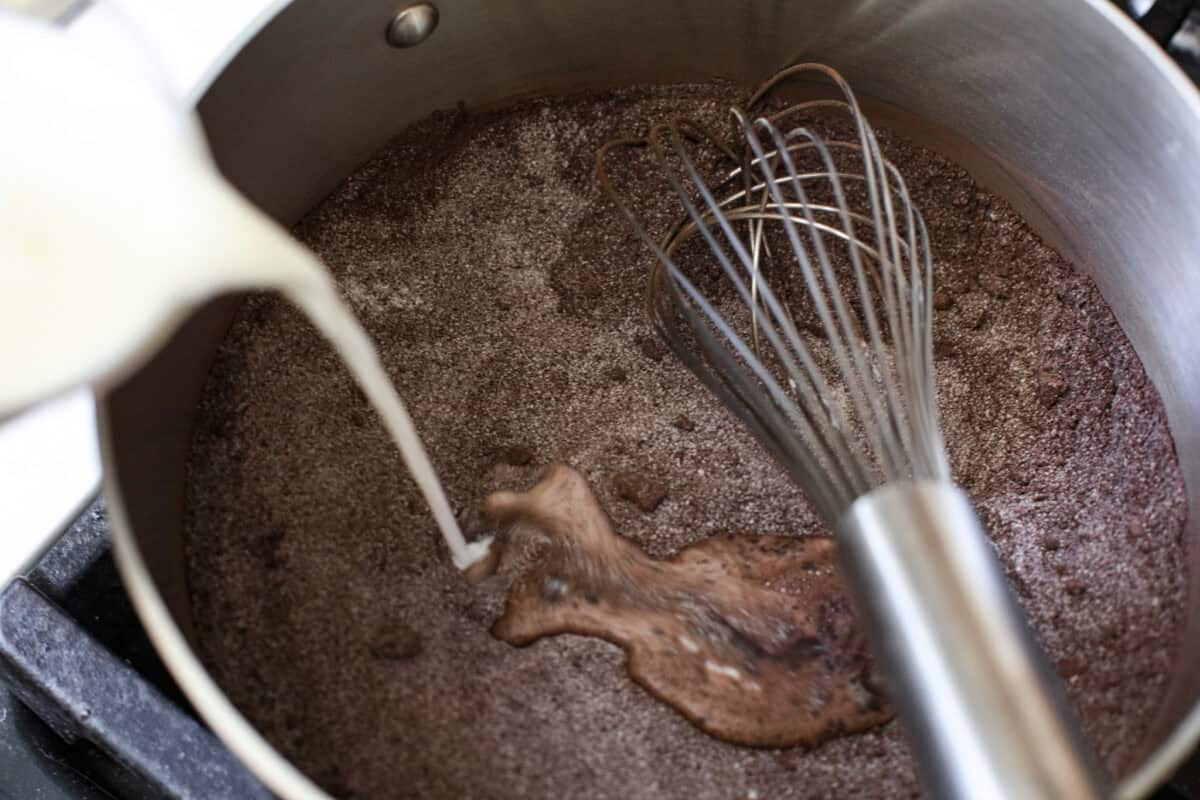 Overhead shot of someone whisking milk into the sugar mixture. 