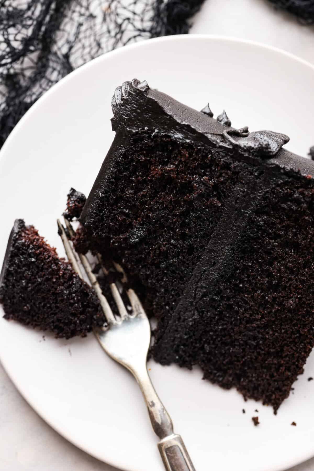 Overhead shot of a plated slice of black velvet cake frosted with black frosting. 