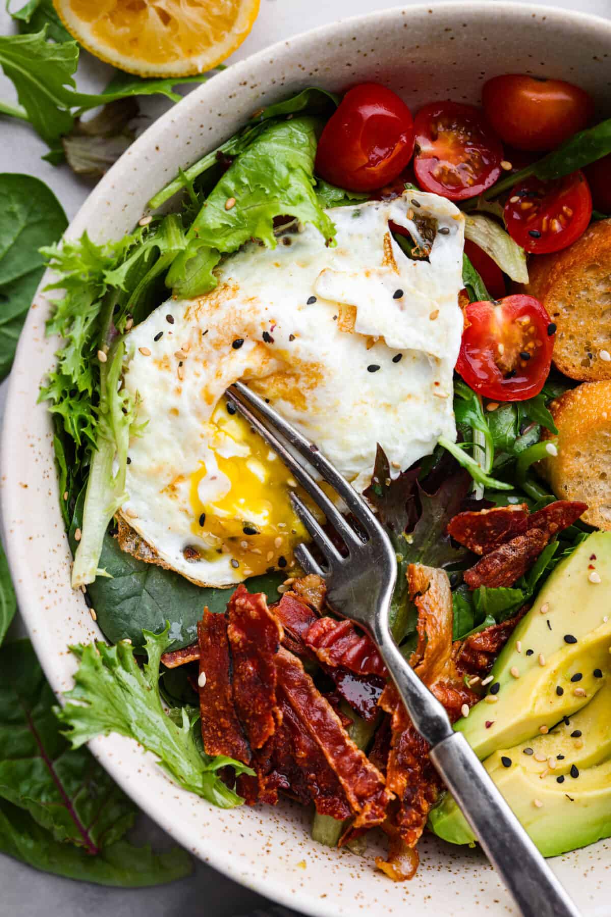 Closeup of breakfast salad and breaking the yolk of the egg open.