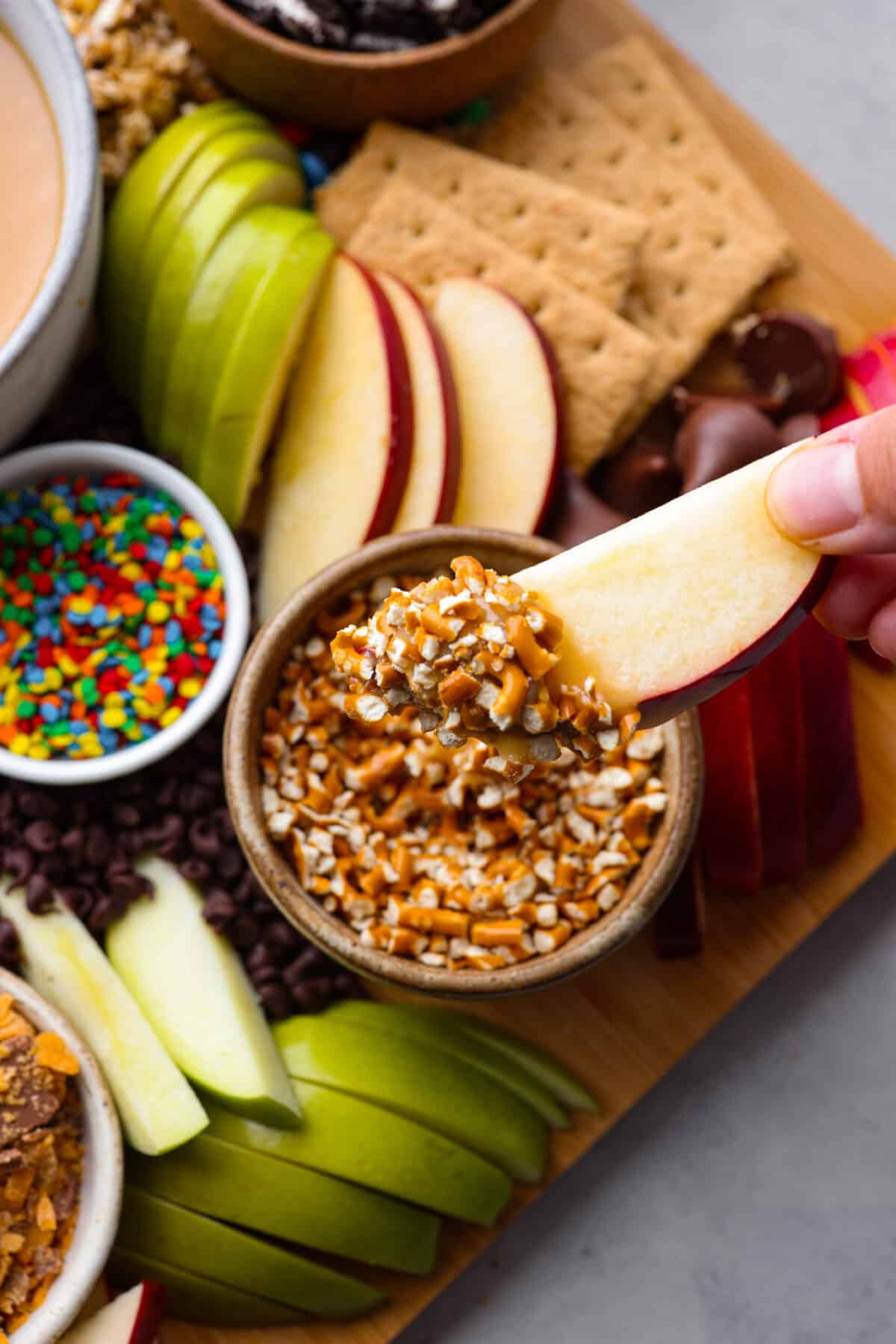 A caramel apple slice that has been dipped in caramel and then crushed pretzels.