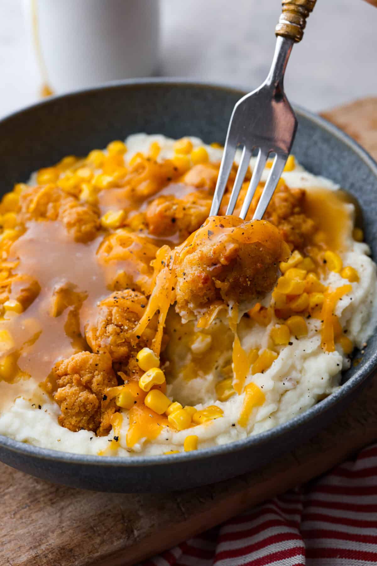 Taking a bite of a KFC Famous Bowl.