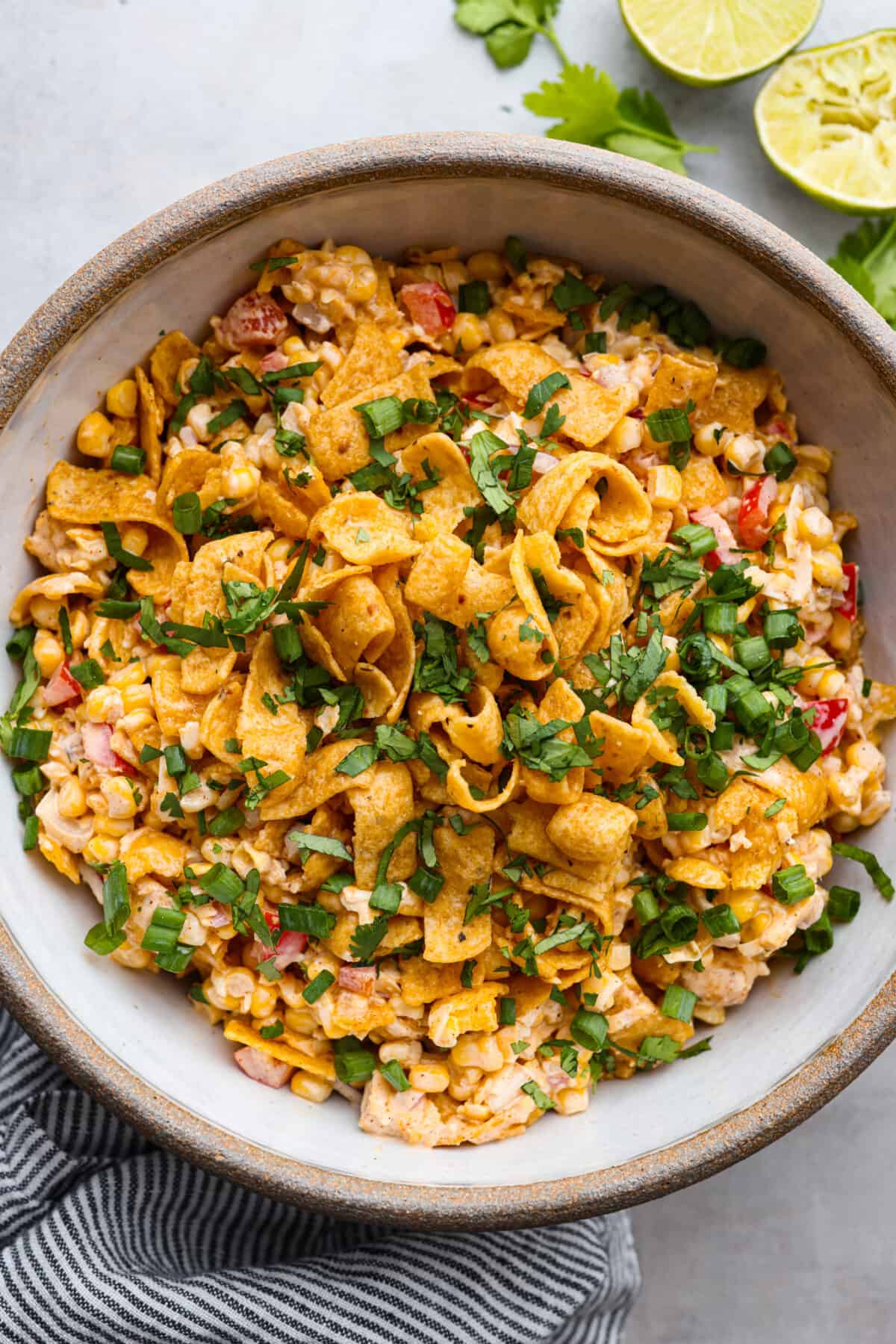 Top view of frito corn salad in a large bowl topped with corn chips, cilantro, and green onions.