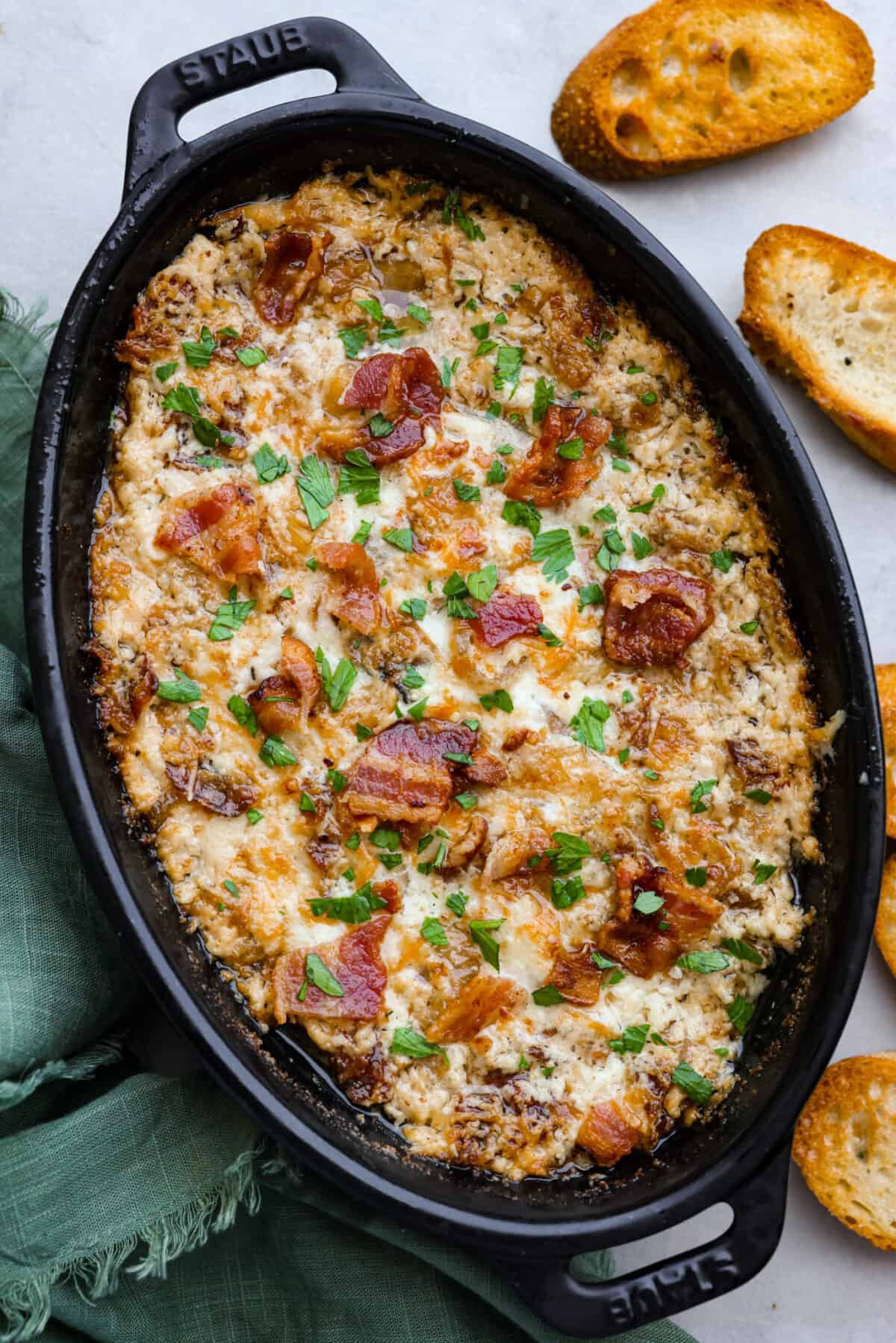 Top-down view of onion and bacon dip in a black cast iron baking dish.