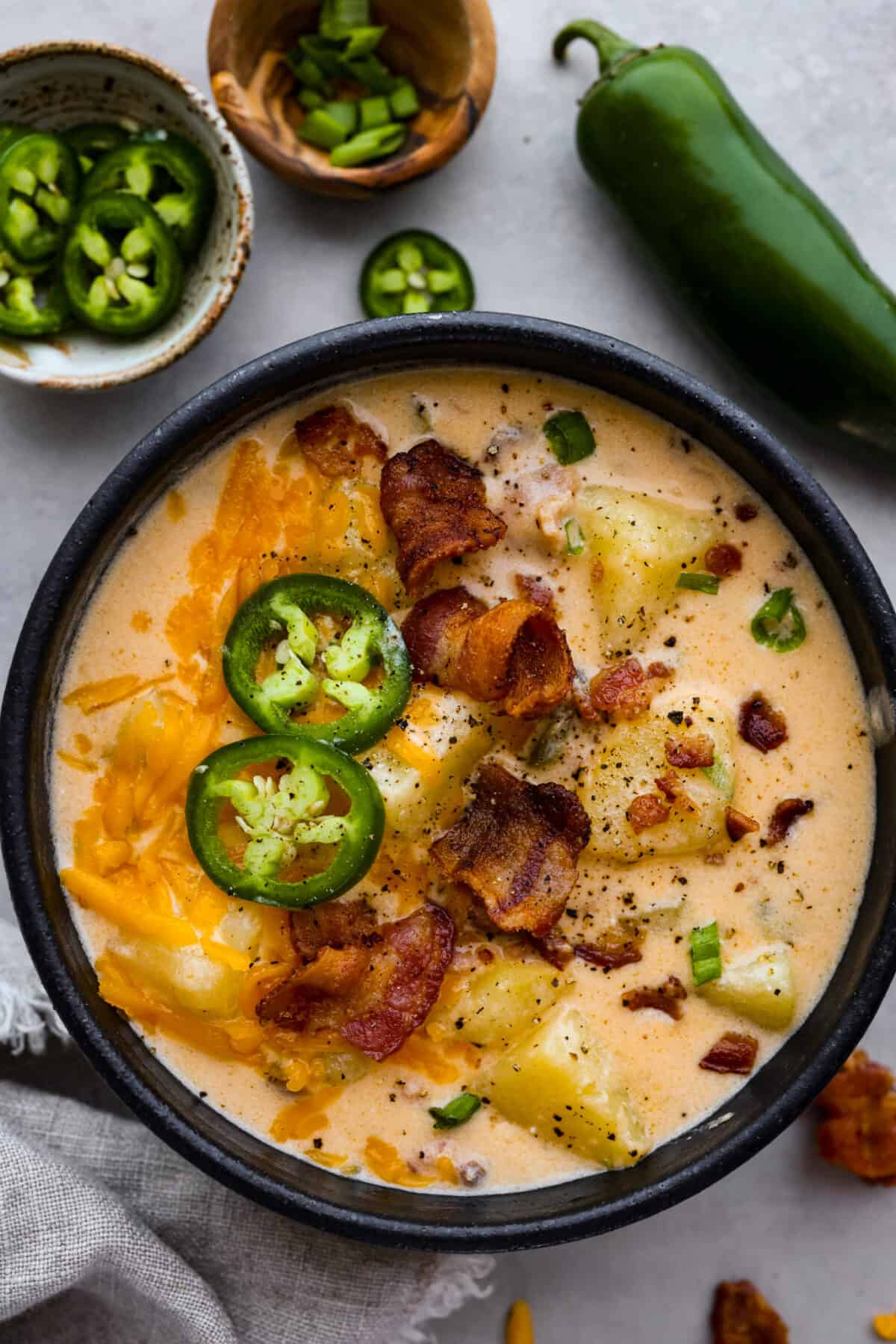 Soup served in a black bowl, surrounded by jalapeños.