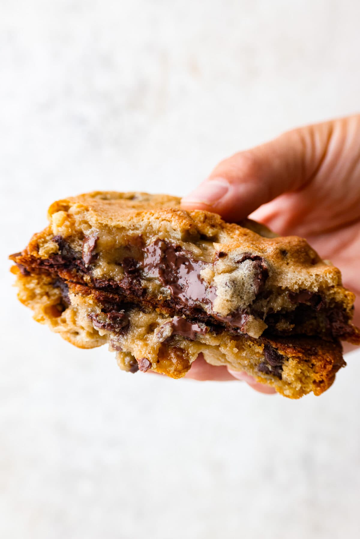 Picking up a copycat levain cookie that has been broken in half.