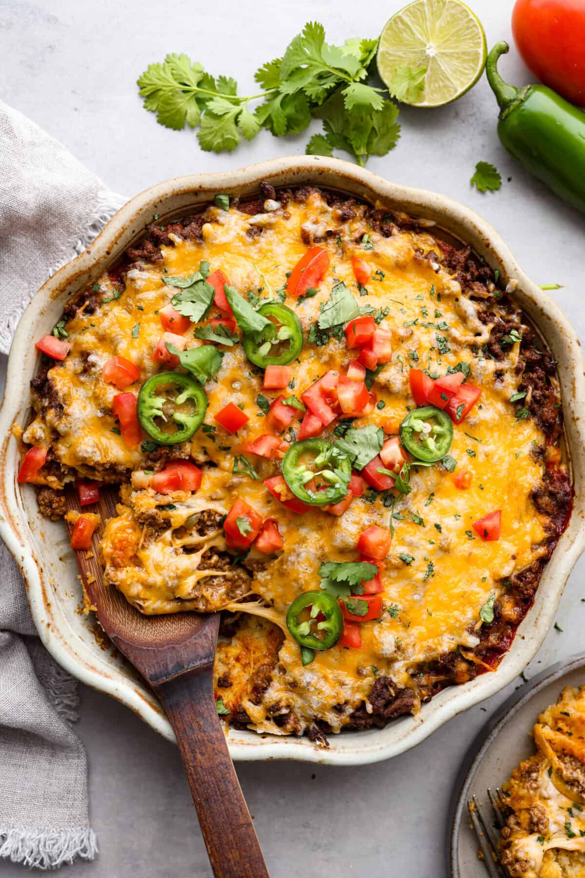 The top view of tamale pie that is garnished with jalapeños, cilantro and tomatoes. 