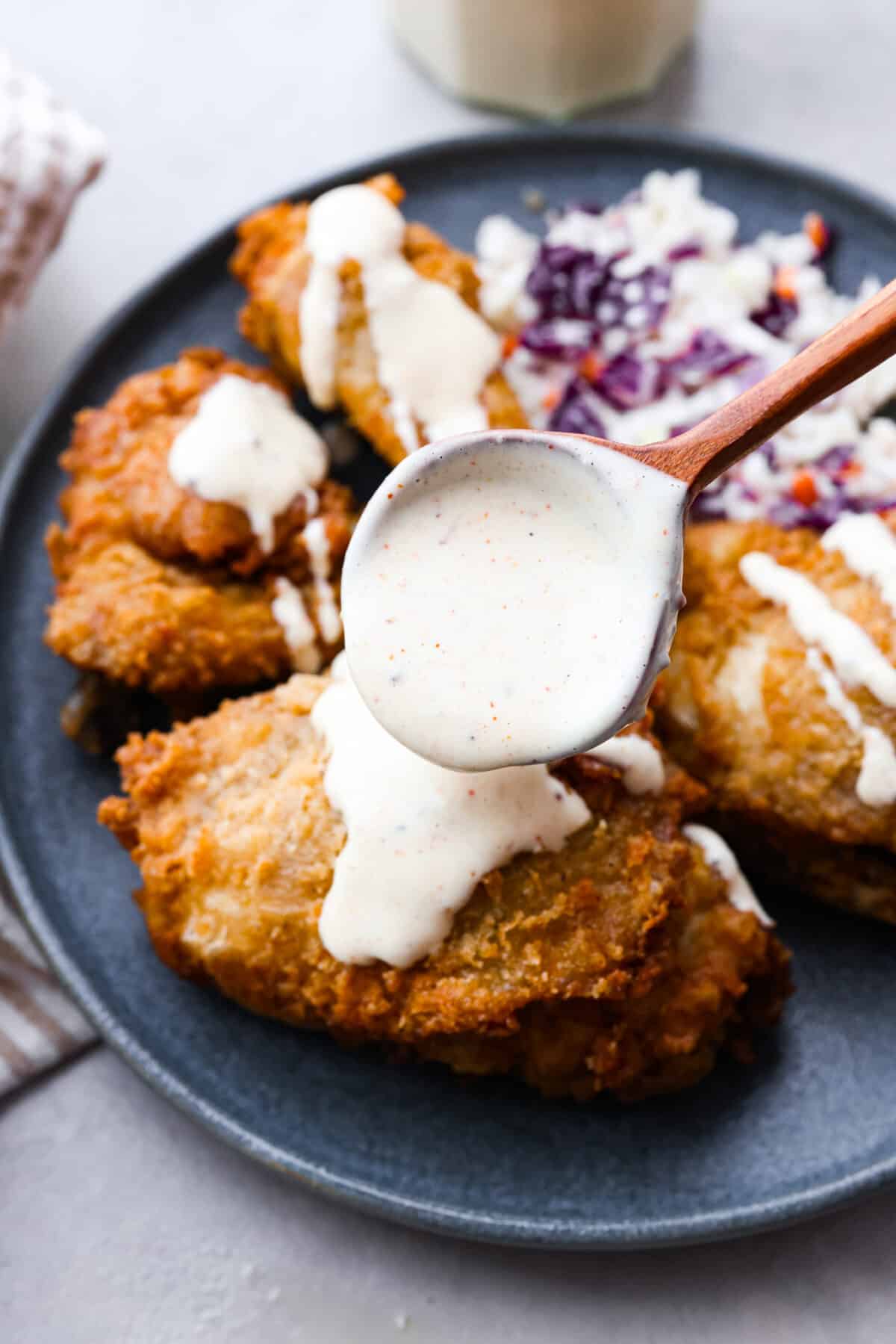 The sauce being drizzled on fried chicken. 