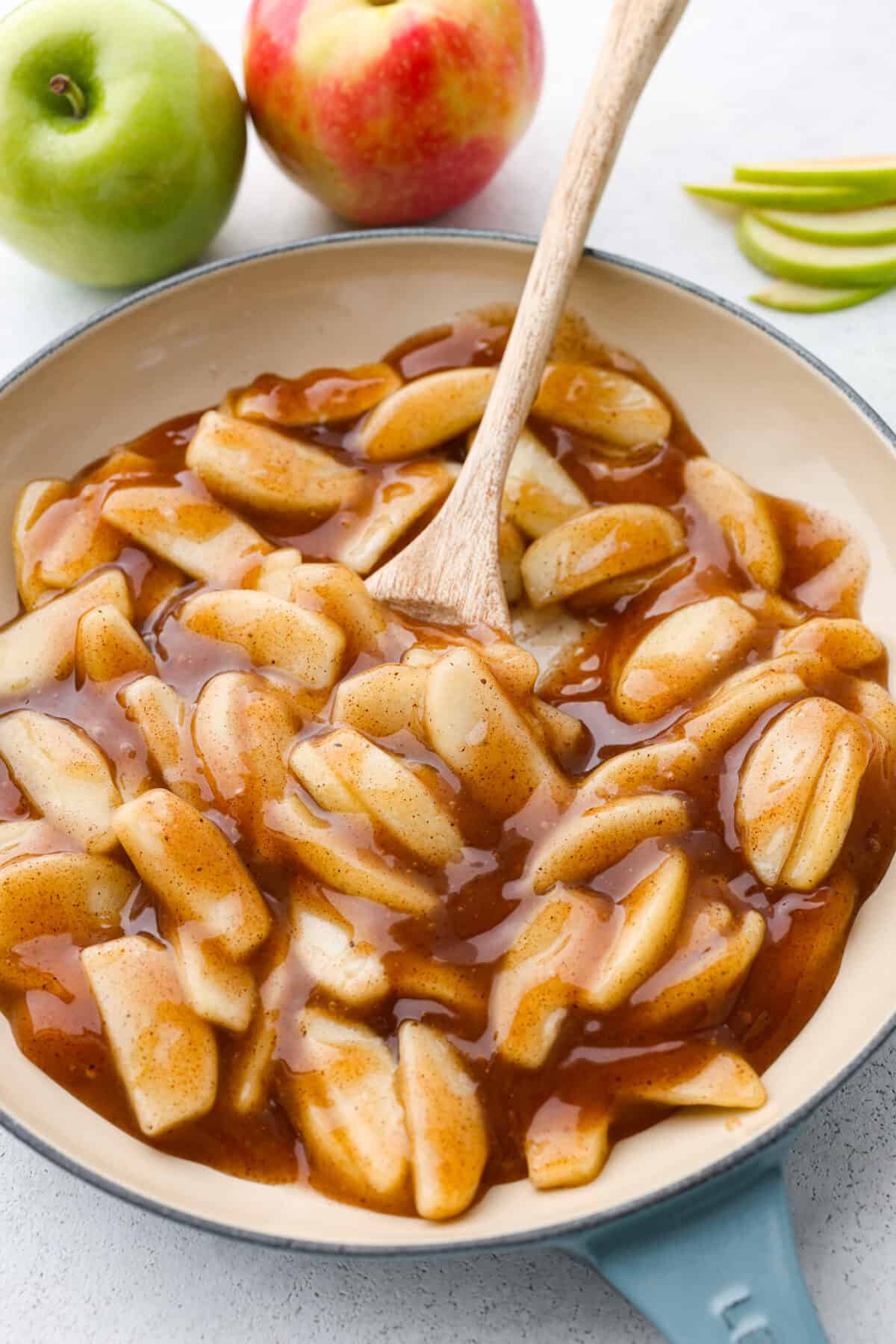 Apple pie filling being stirred in a blue and white skillet.