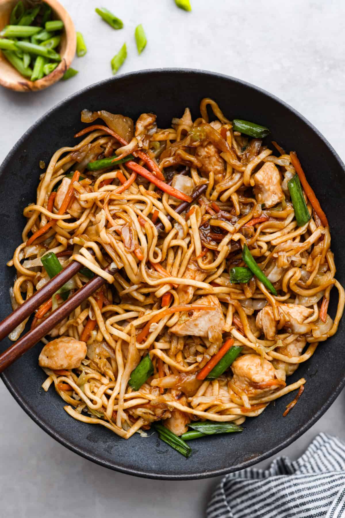 Top-down view of chicken chow mein served in a black bowl.