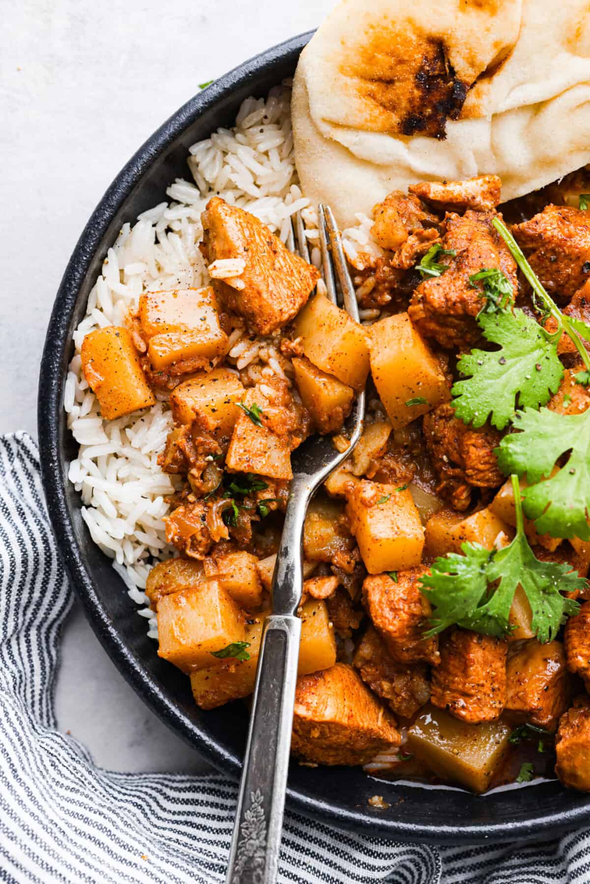 A serving of chicken curry with rice and naan.