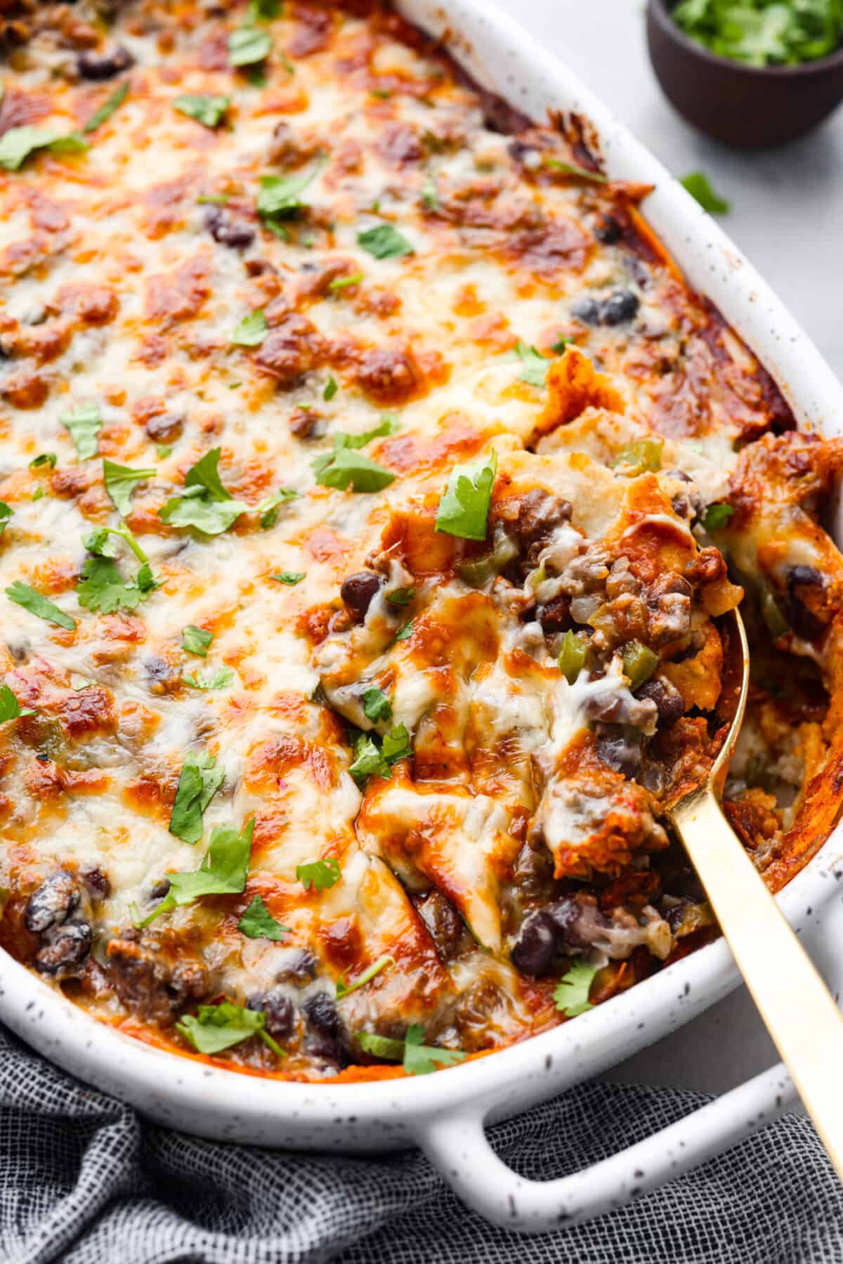 Hero image of enchilada casserole in a white baking dish.