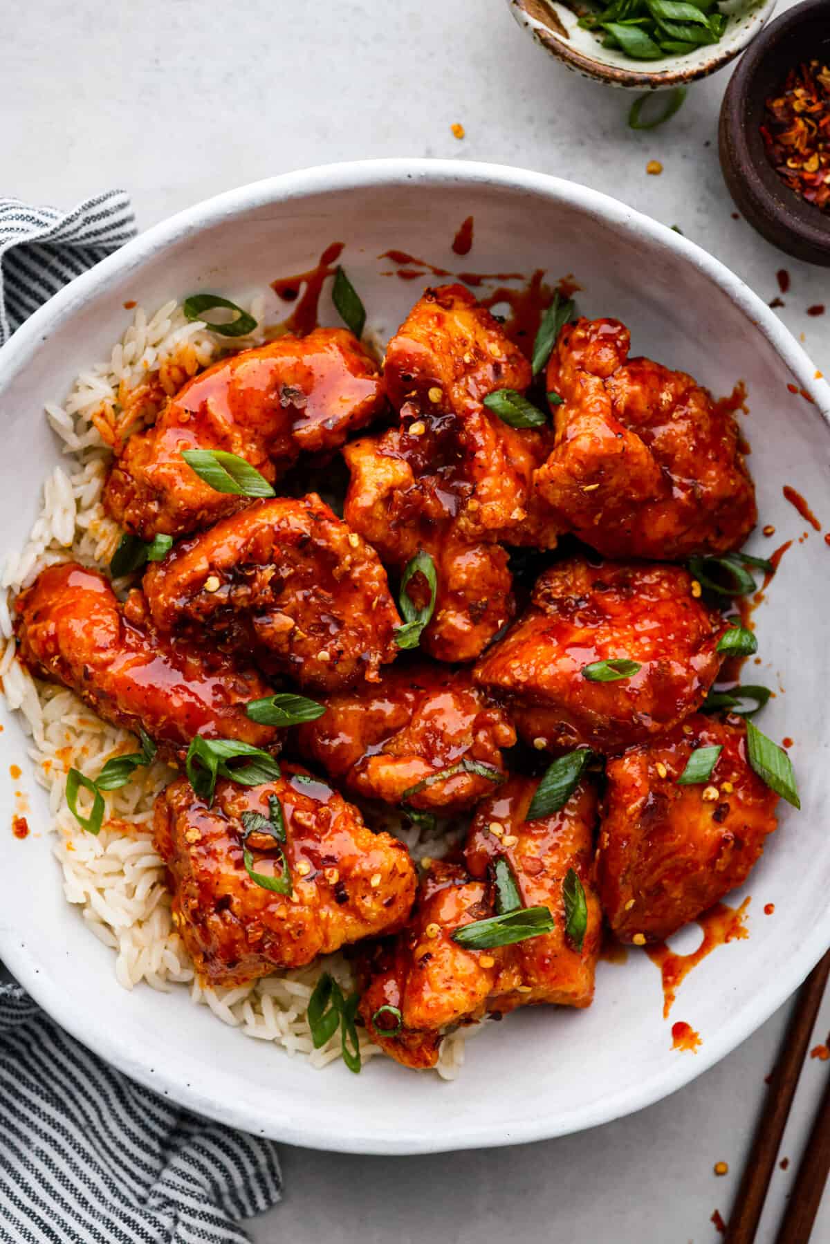 Korean fried chicken served over rice in a white bowl.