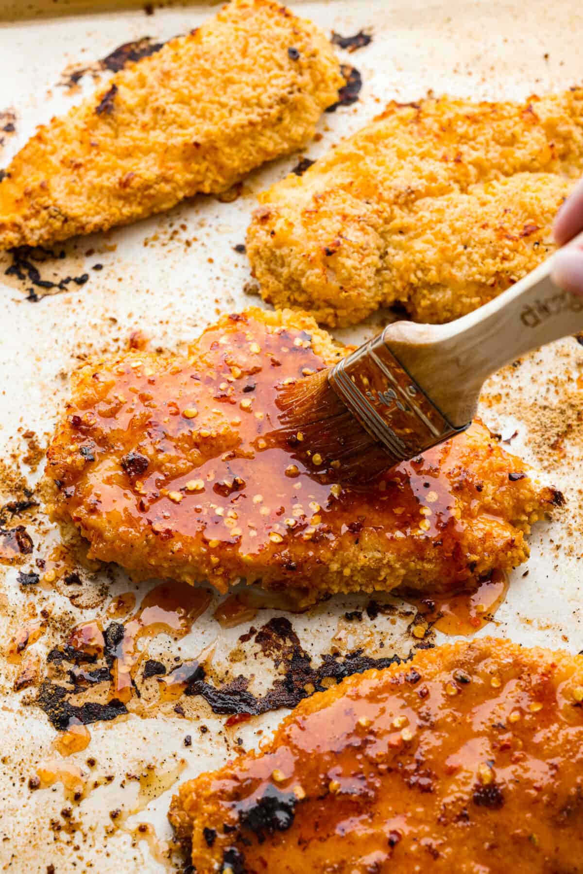 Brushing sauce over a piece of hot honey chicken.