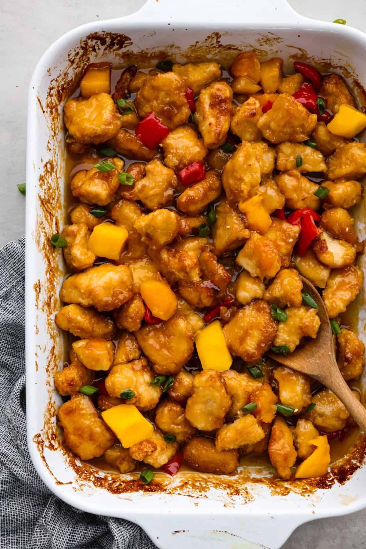 Top-down view of mango chicken in a white baking dish.