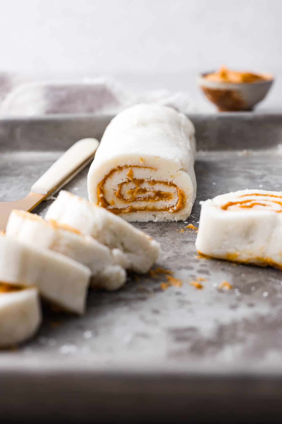 Side shot of a peanut butter pinwheel candy roll with slices in the foreground. 