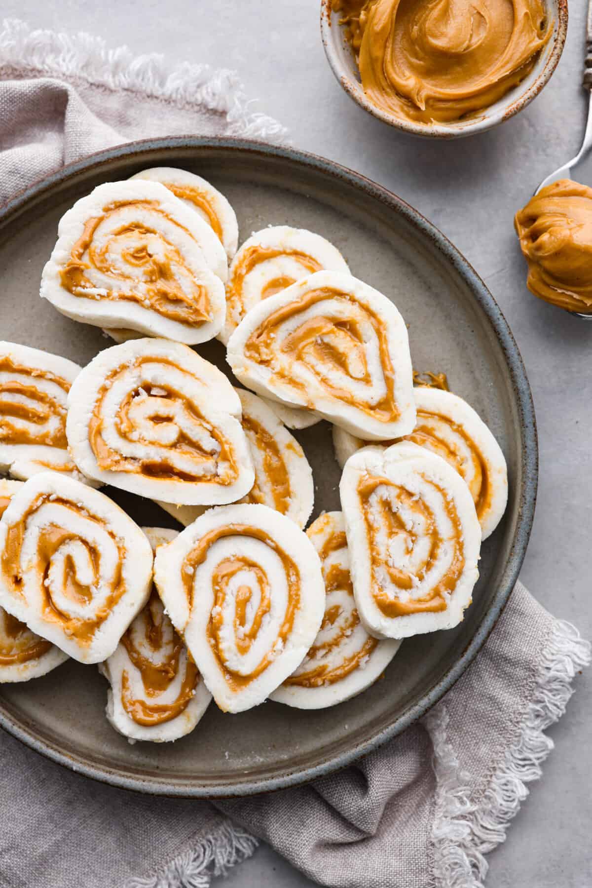 Overhead shot of sliced peanut butter pinwheels candy stacked on a plate. 