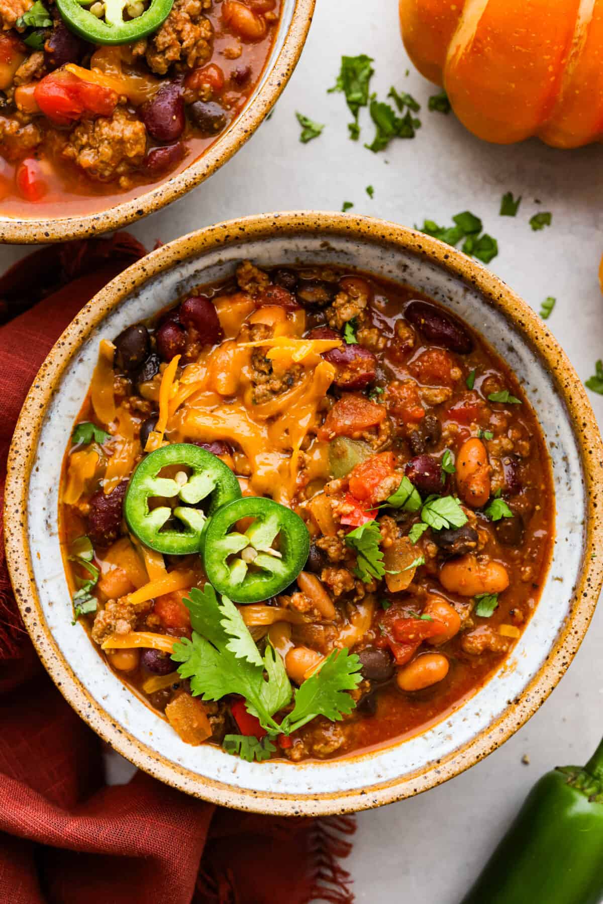 Overhead shot of a bowl of pumpkin chili topped with jalapeños, cheese and cilantro. 