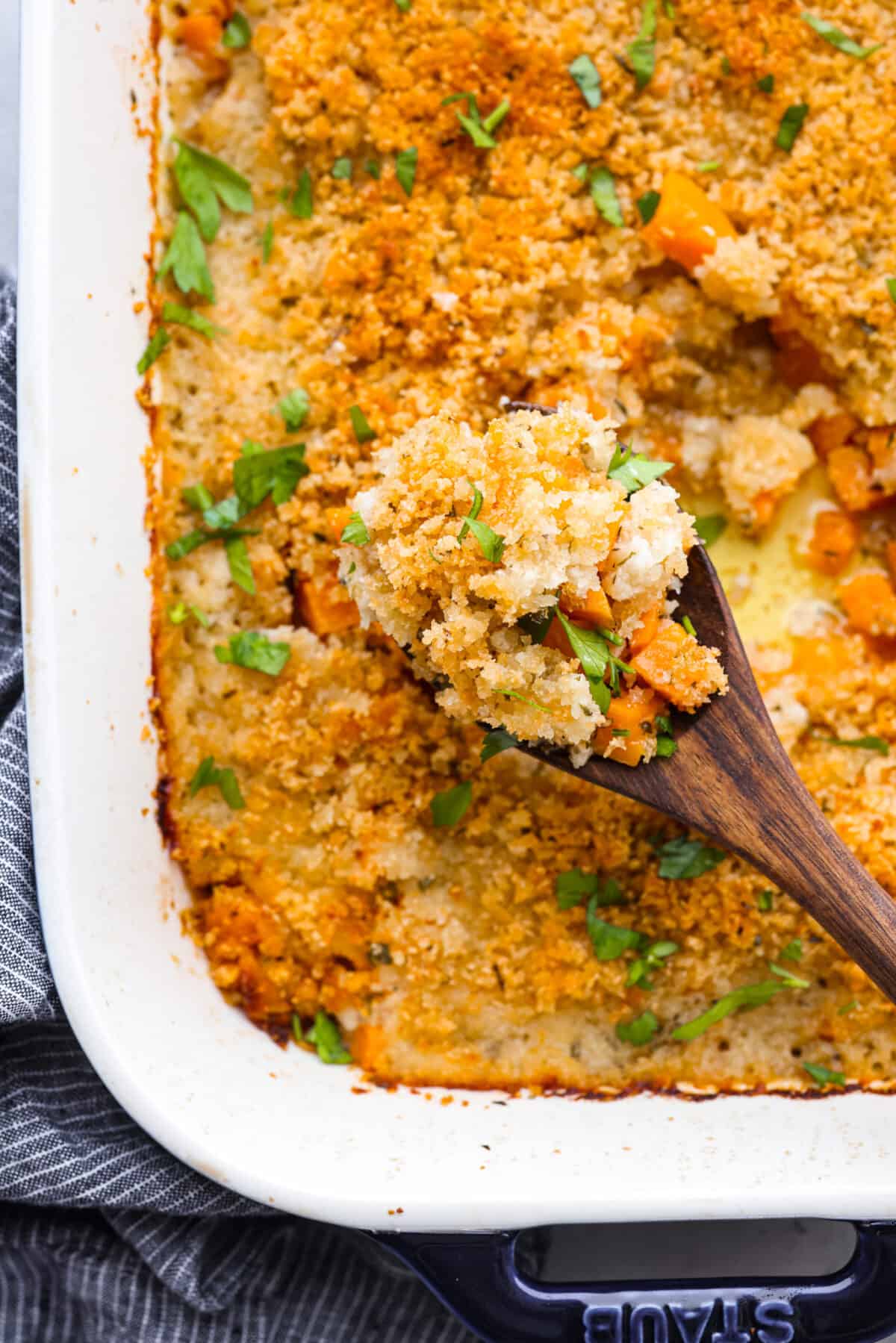 Closeup of a spoonful of casserole on a wooden spoon.