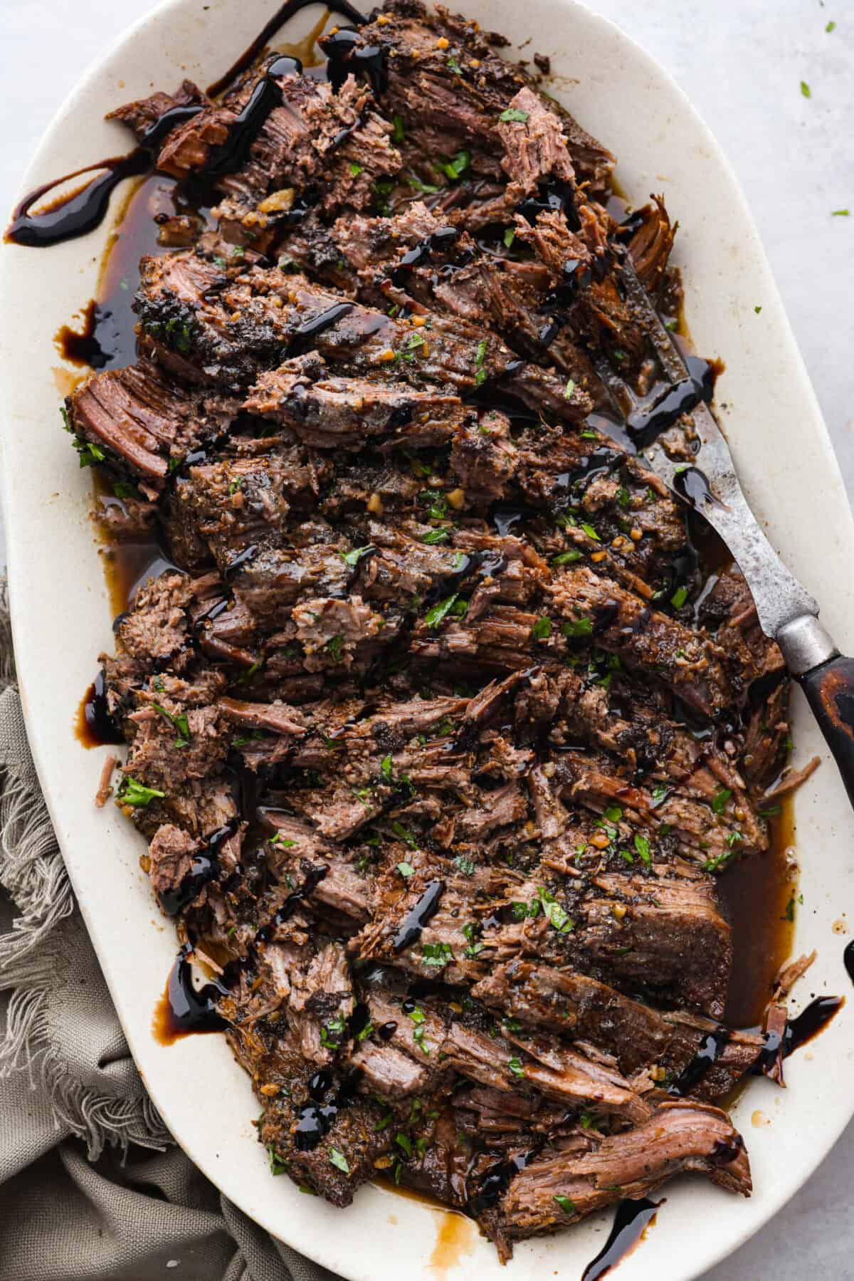 Top-down view of slow cooker balsamic beef shredded into pieces.