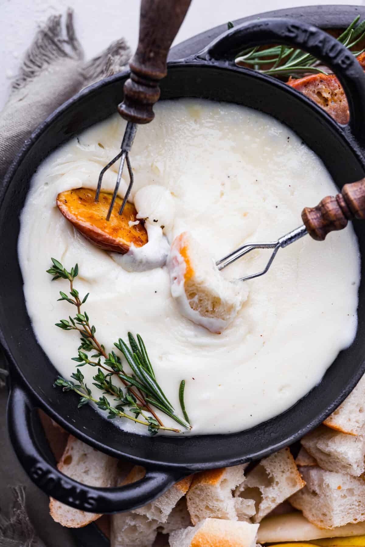 Dipping bread and potatoes into the cheese.