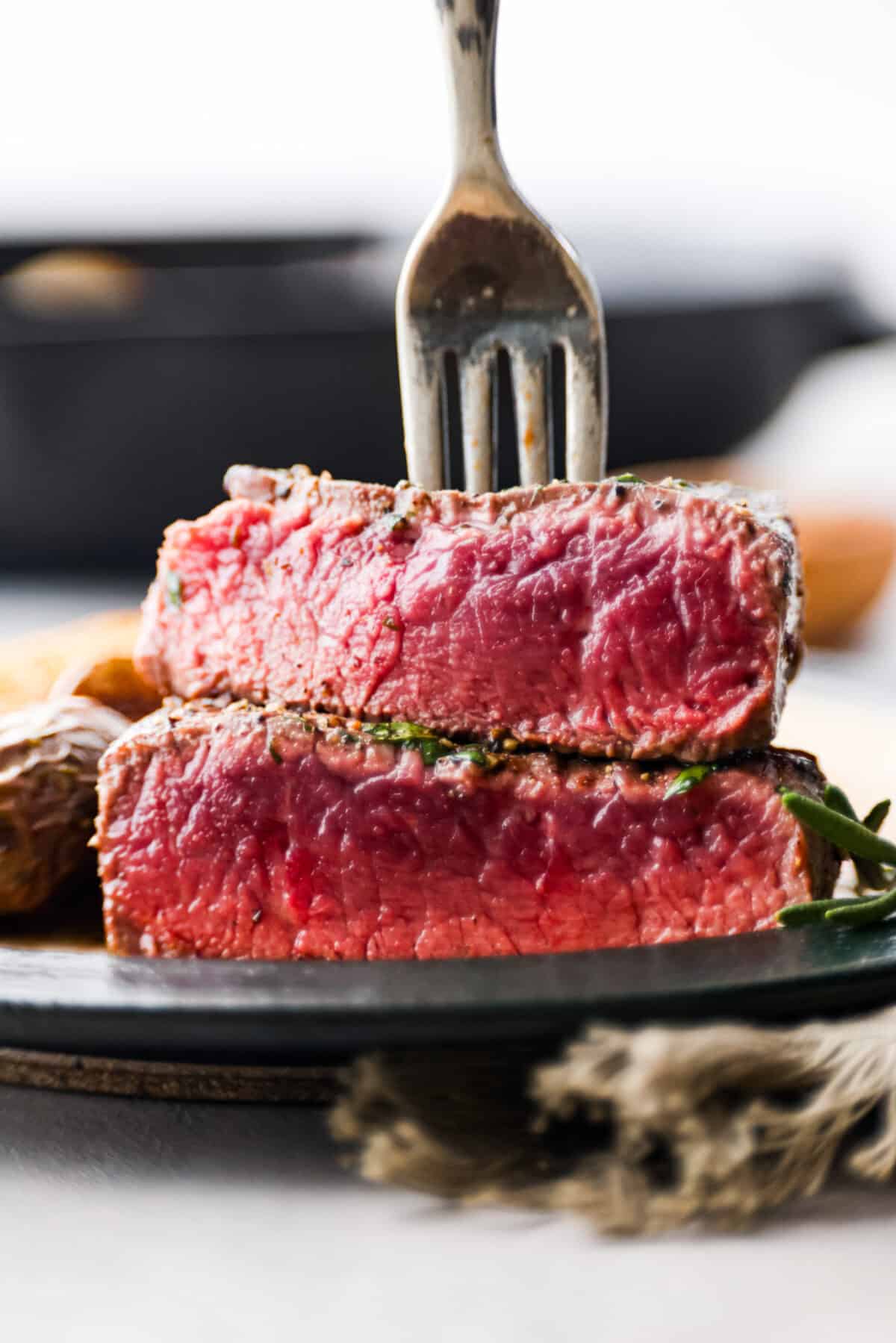 Close view of sliced filet mignon stacked on a plate with a fork in it.