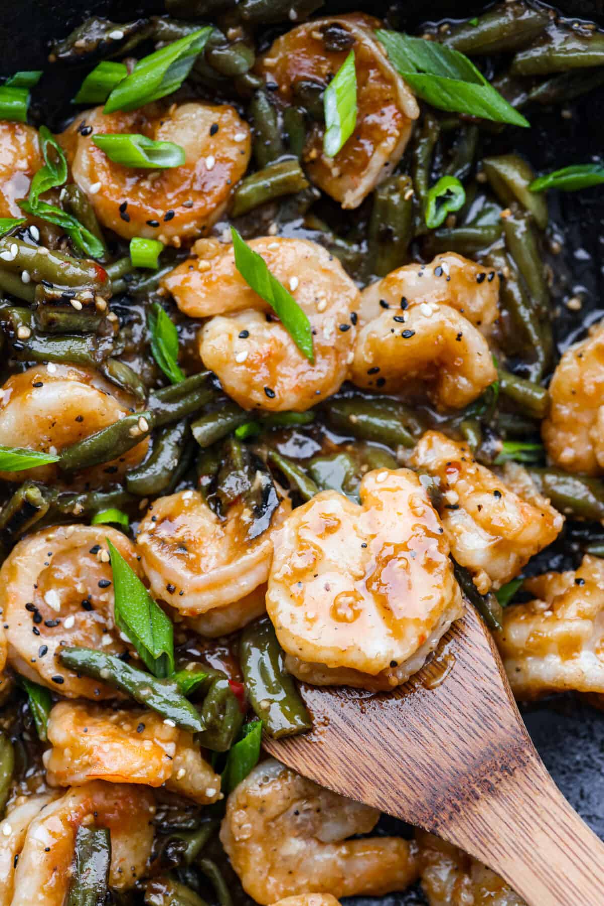 Closeup of Hunan shrimp being stirred with a wooden spoon.