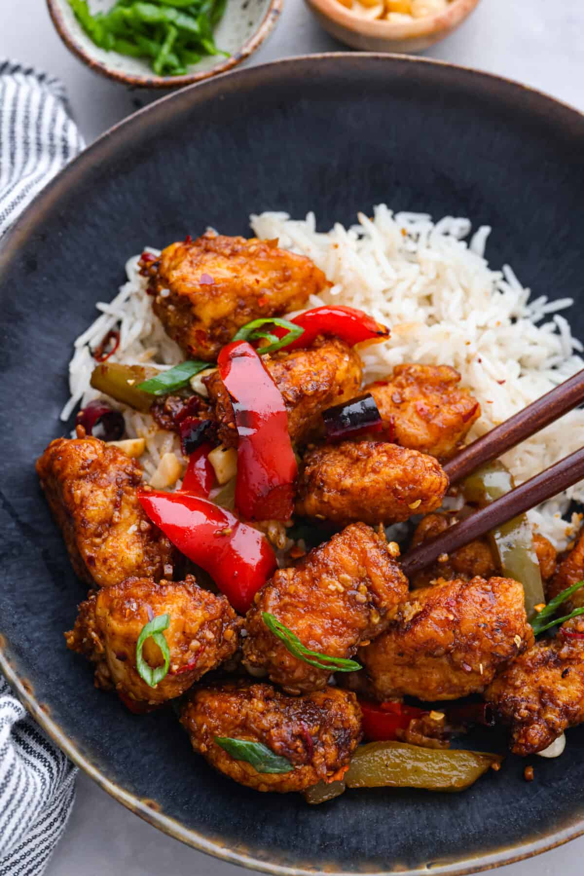 A serving of chicken and rice in a black bowl.