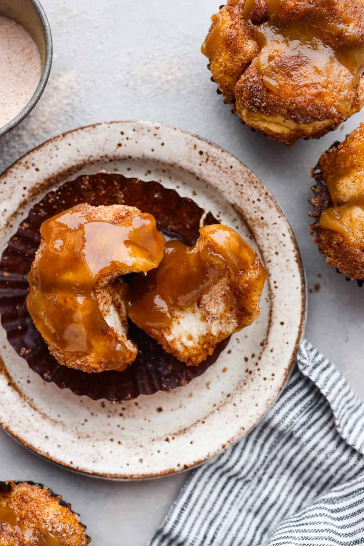 A monkey bread muffin on a stoneware plate. It is torn in half.