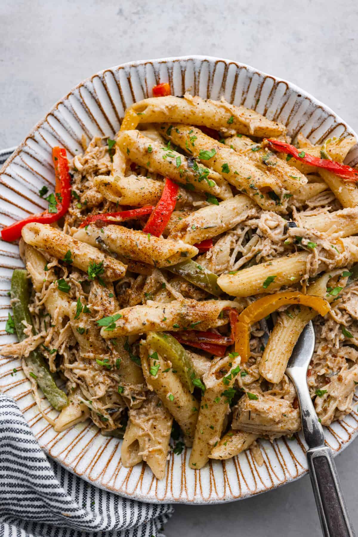 Rasta pasta served in a white scalloped stoneware bowl.