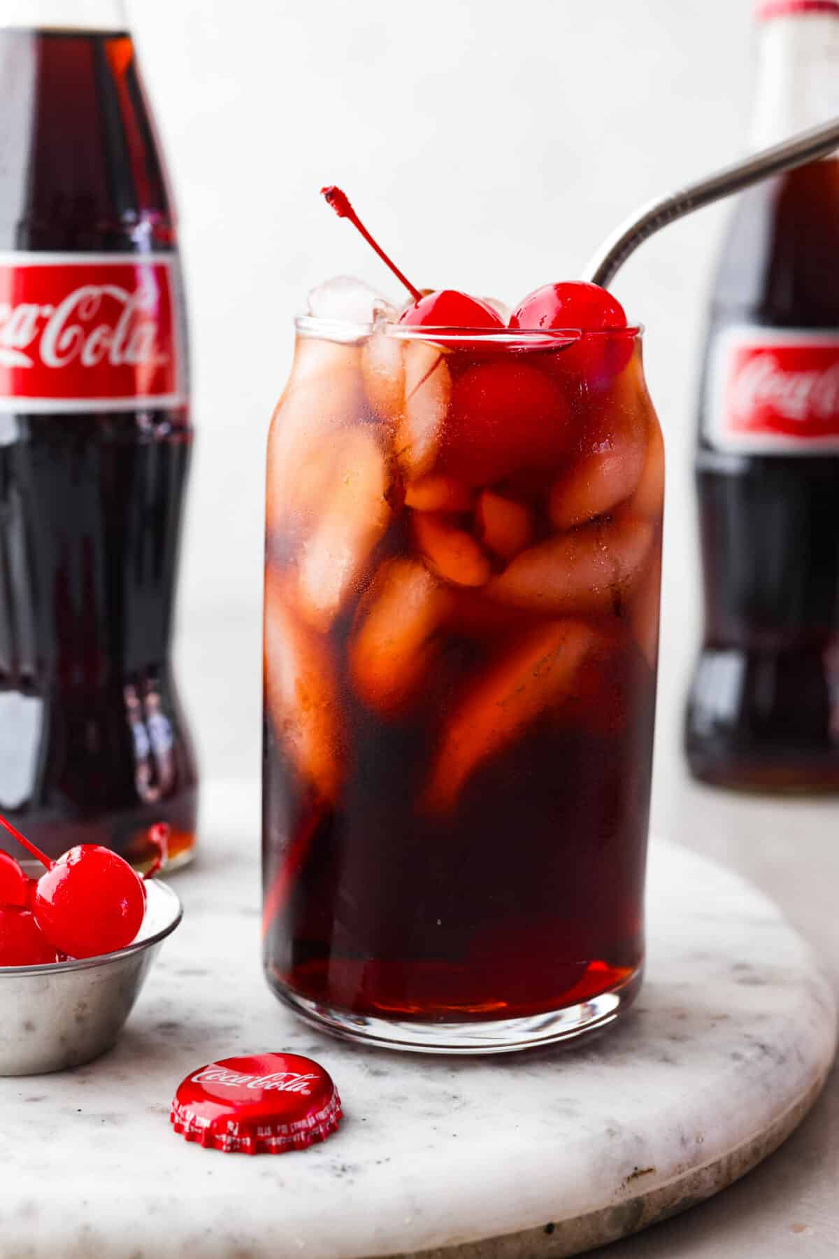 Close view of Roy Rogers drink in a tall glass with ice and cherries on top.