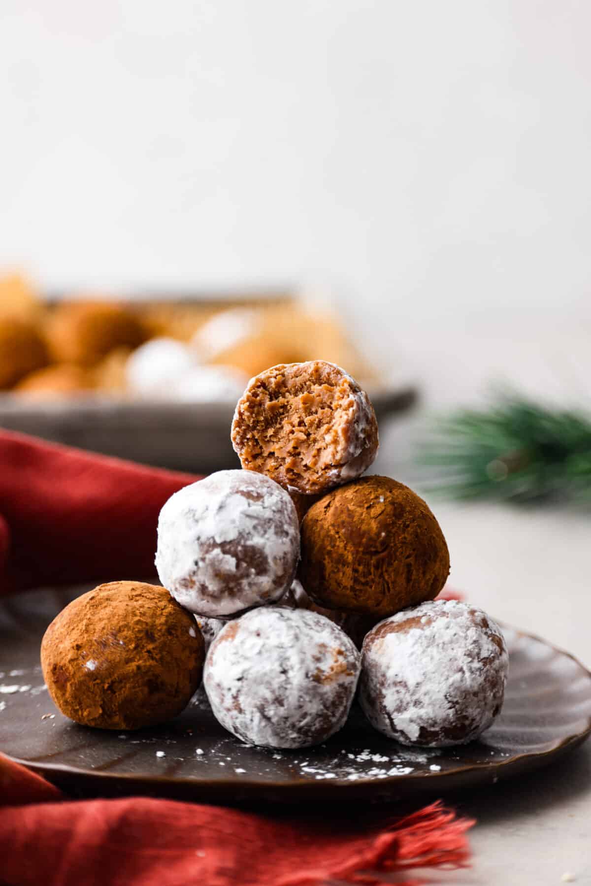 Close view of rum balls stacked on a brown plate.