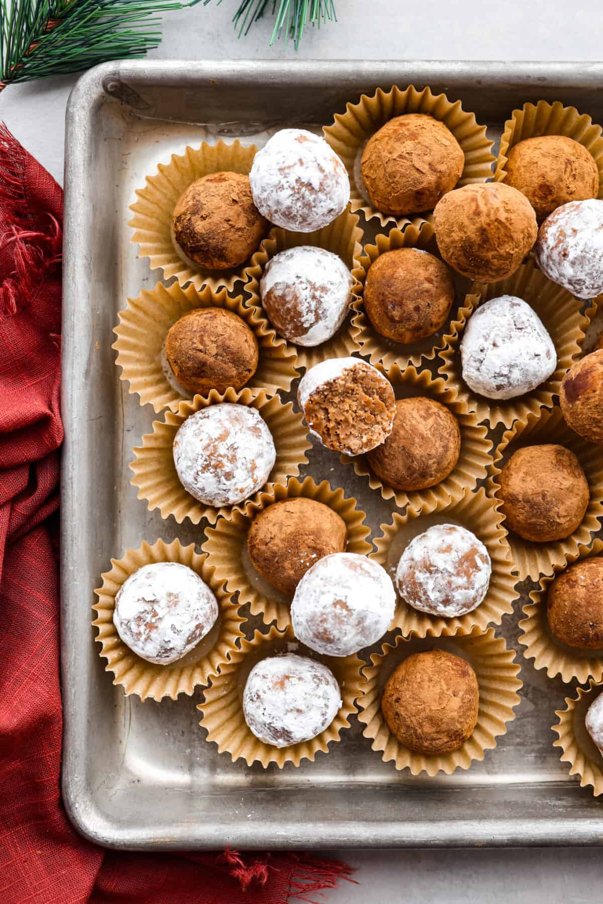 Top close view of rum balls in mini muffin cups and stacked on a sheet pan.