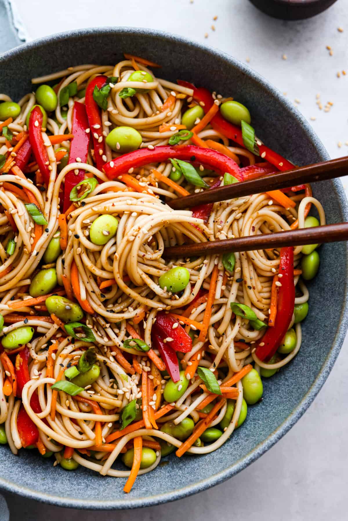 Closeup of soba pasta salad and brown chopsticks.