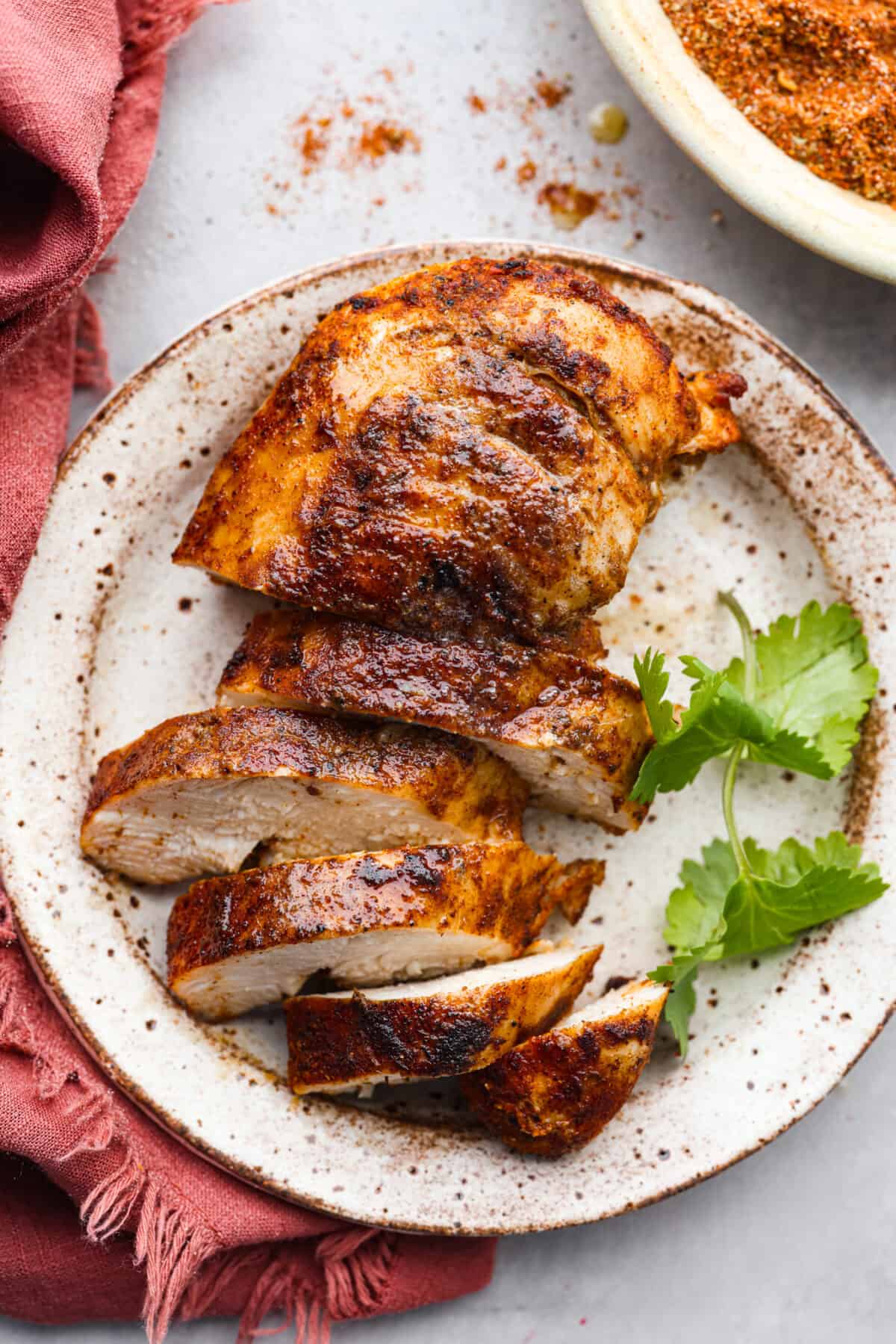 Close view of sliced and seasoned chicken on a plate.