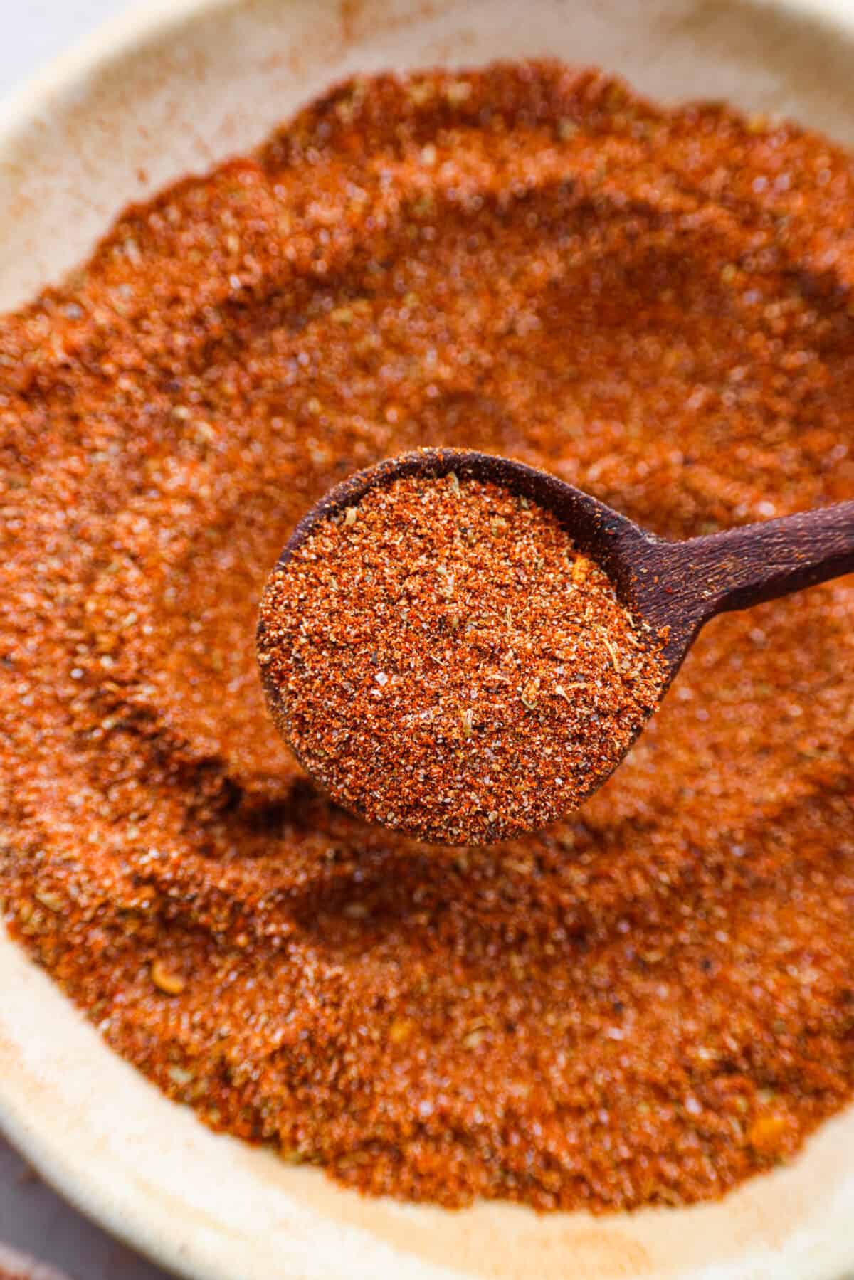 Close view of a wood spoon lifting up a scoop of seasoning.