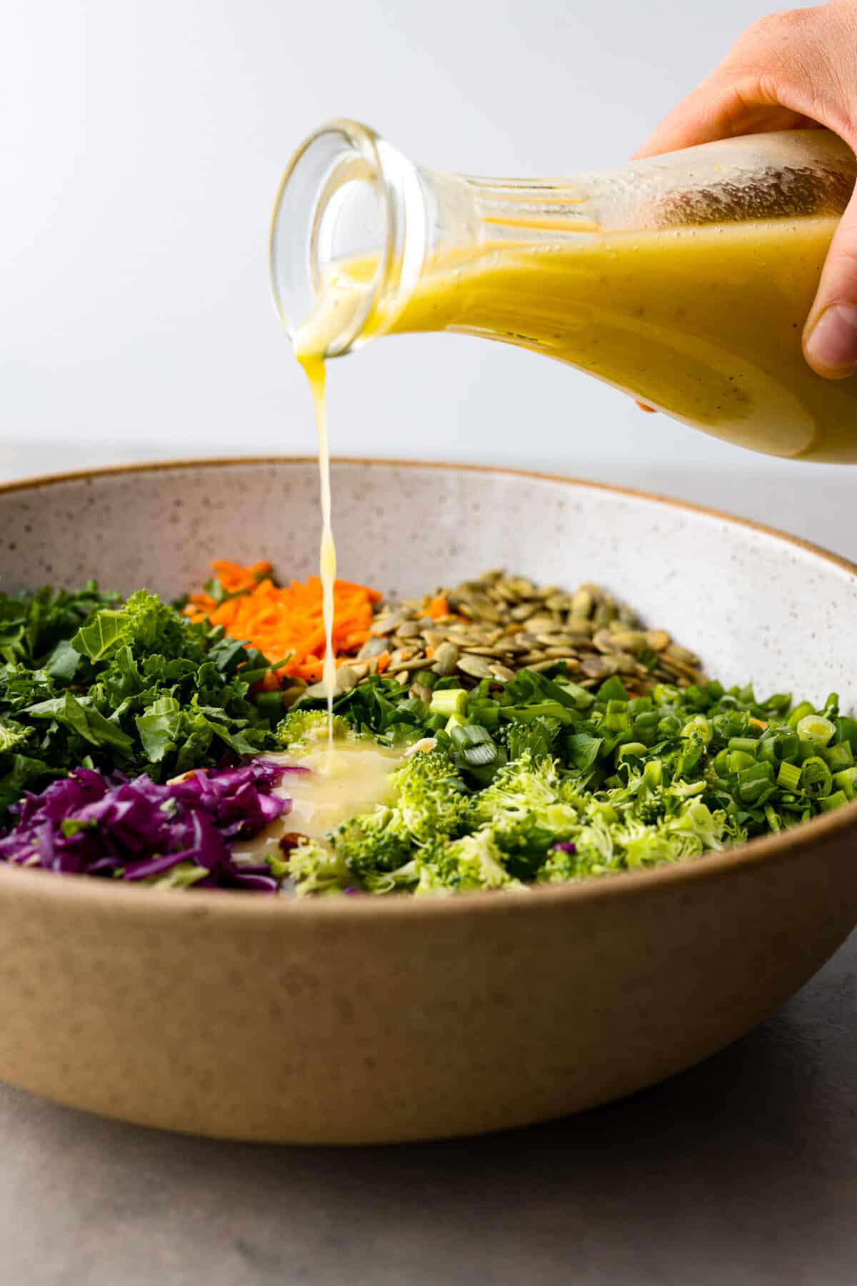 Side view of the dressing pouring over the salad ingredients.