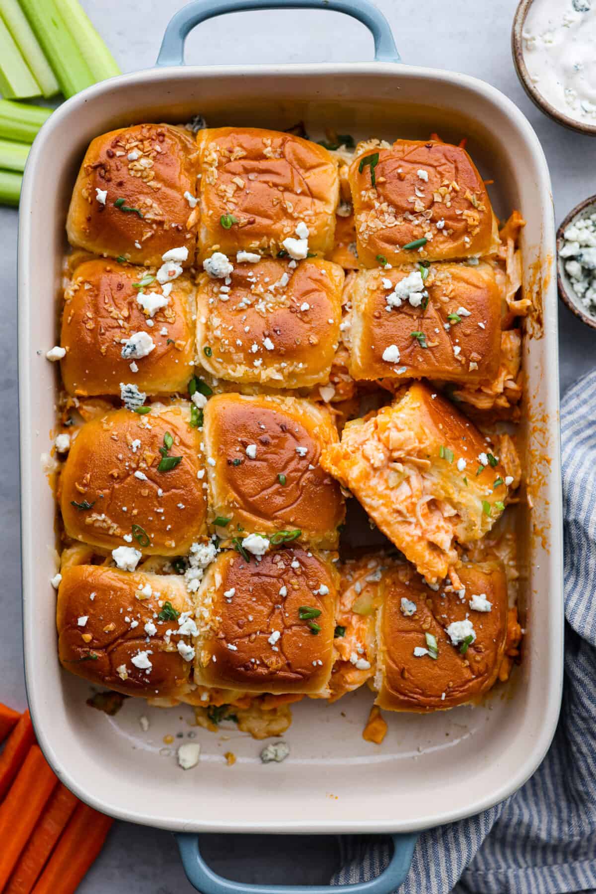 The top view of sliders in a casserole dish. one is pulled out and turned so that you can see the inside of the roll. 