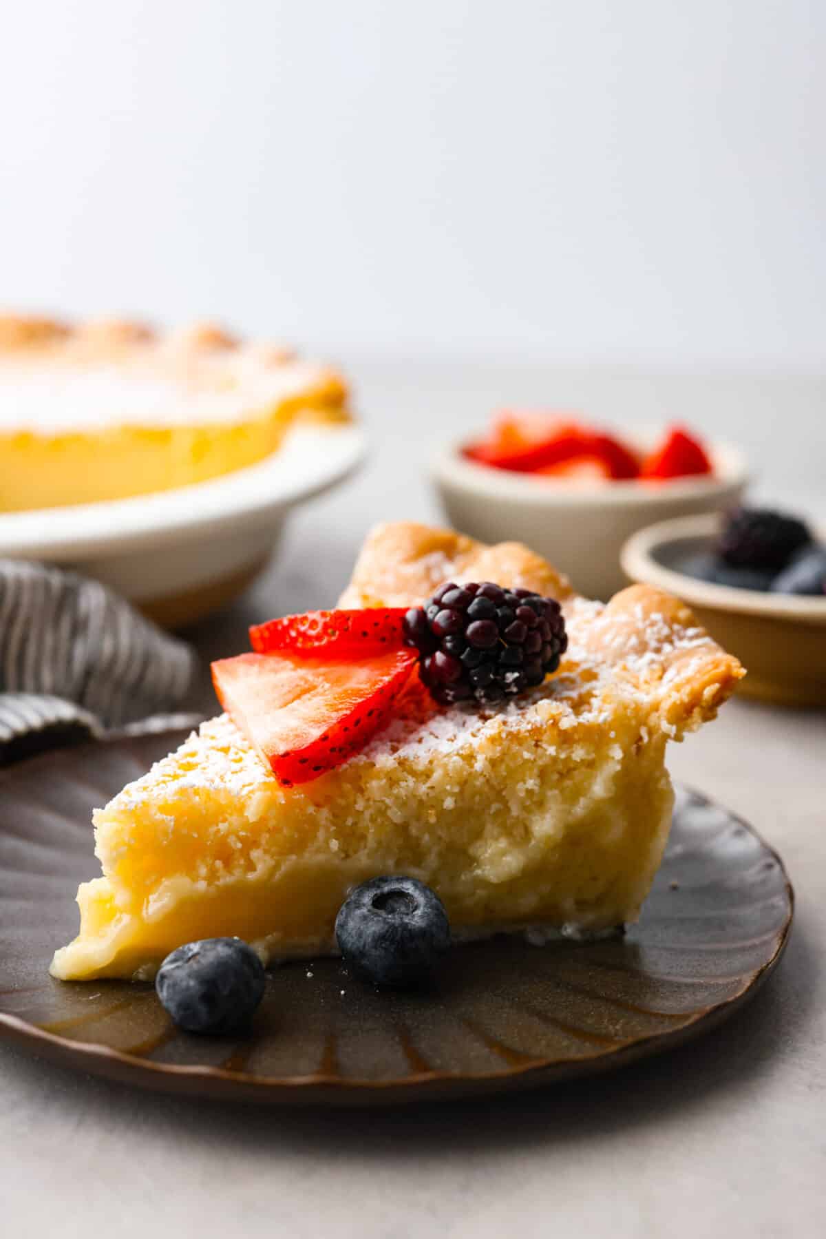 A slice of pie topped with strawberries, blackberries, and blueberries