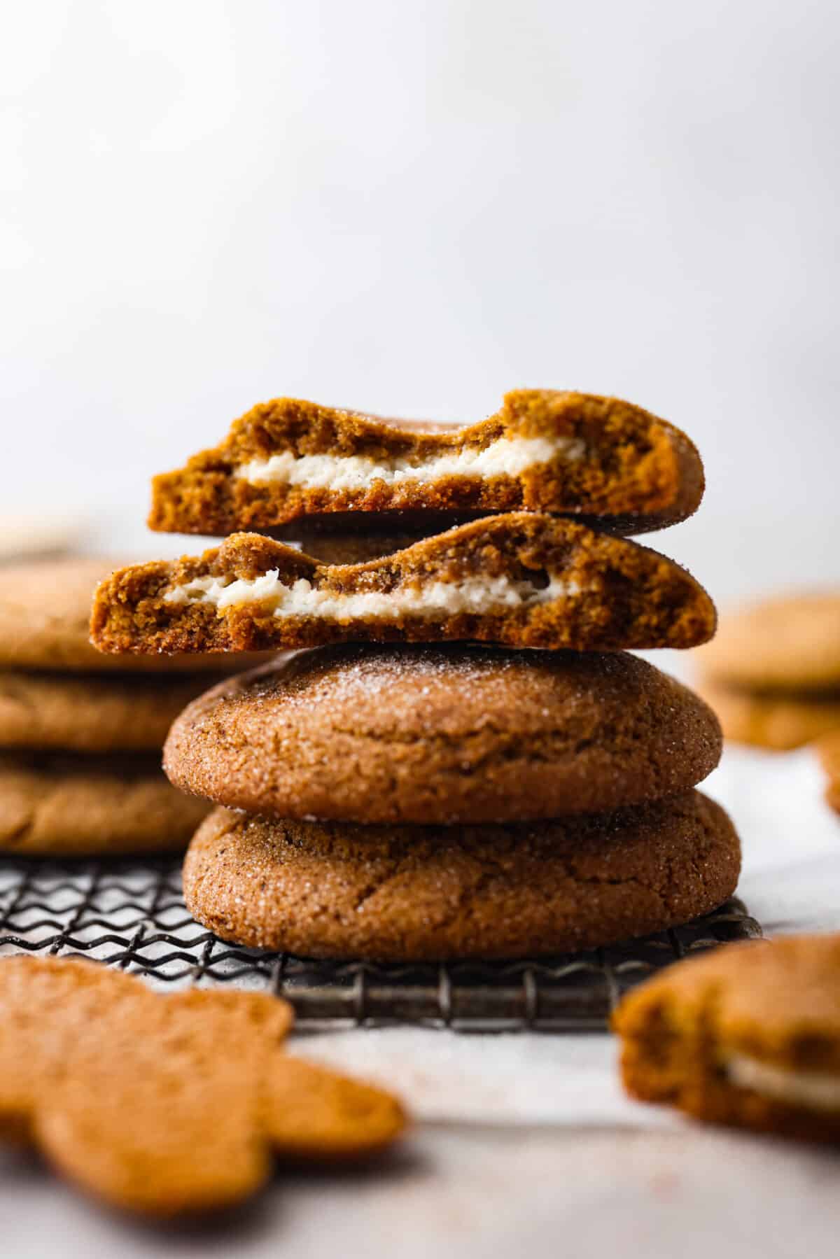 4 stuffed gingerbread cookies stacked on top of each other. 2 are ripped in half so the filling can be seen.