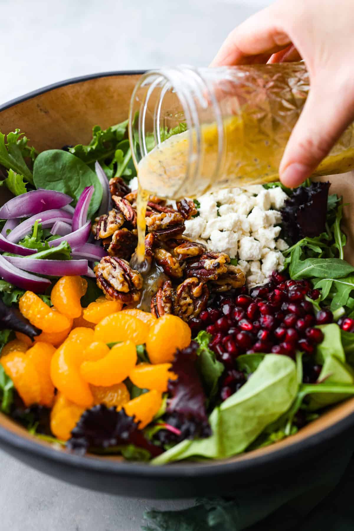 Close side view of the vinaigrette pouring over the salad ingredients. 