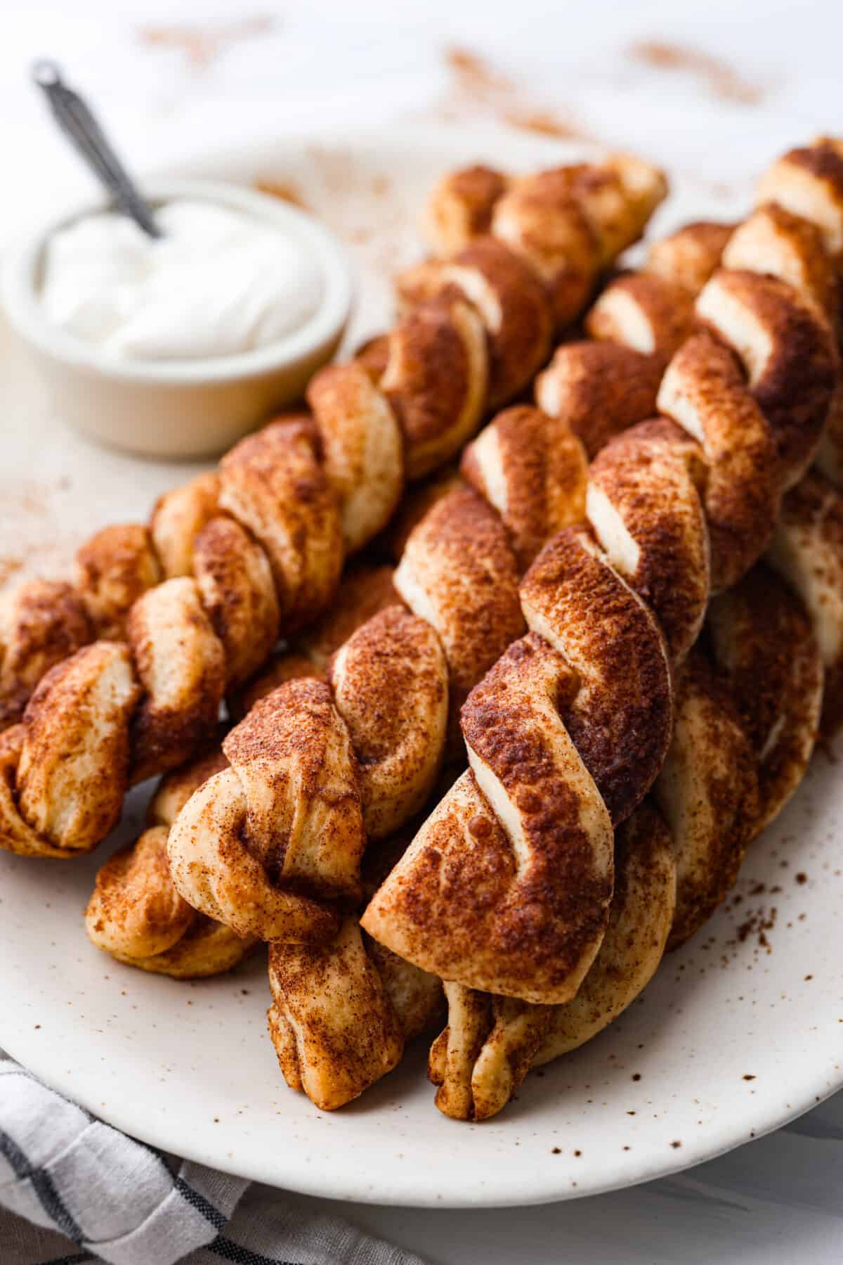 Close view of cinnamon roll breadtwists stacked on a plate.