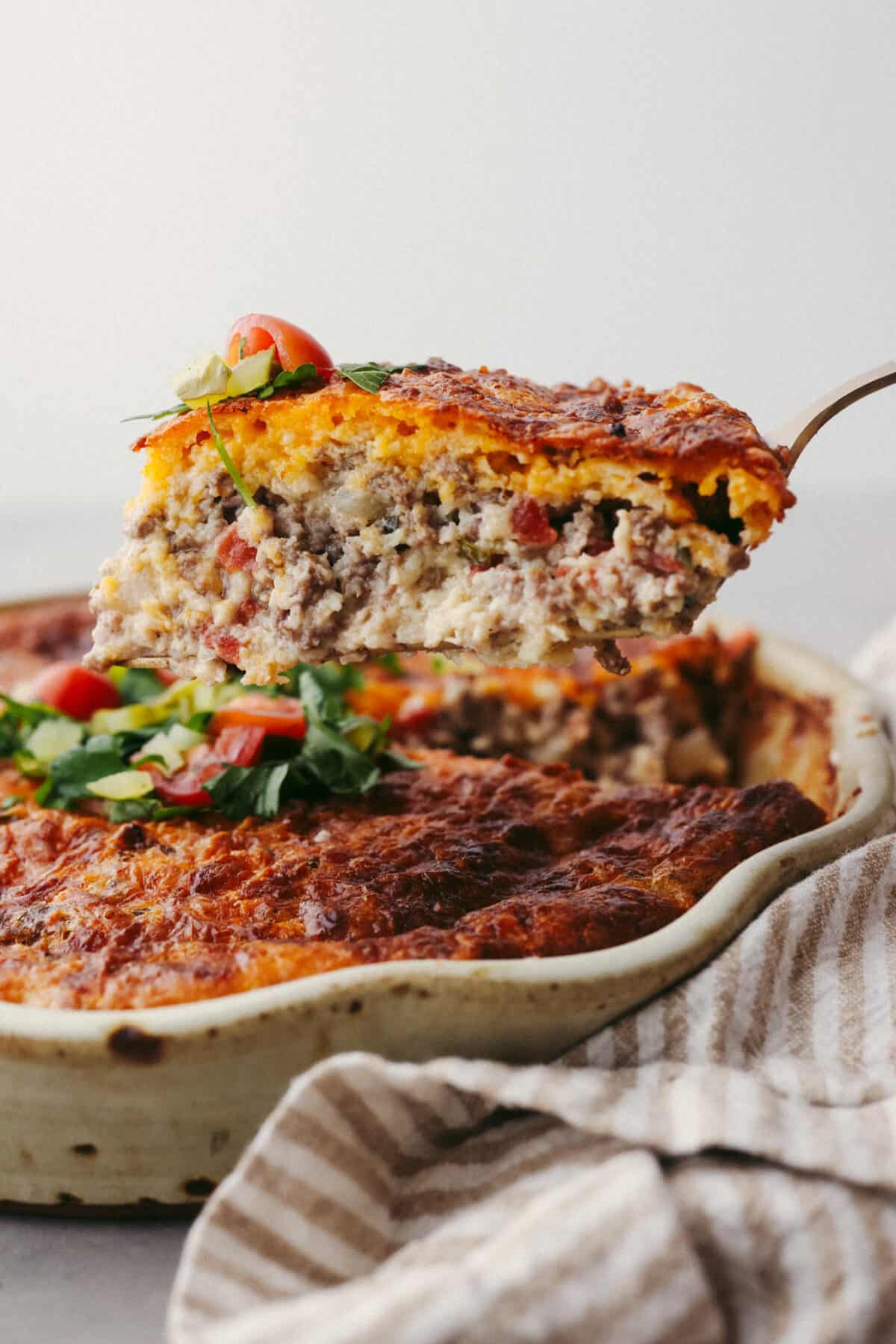 Side view of a slice of cheeseburger pie lifting from the pie dish.