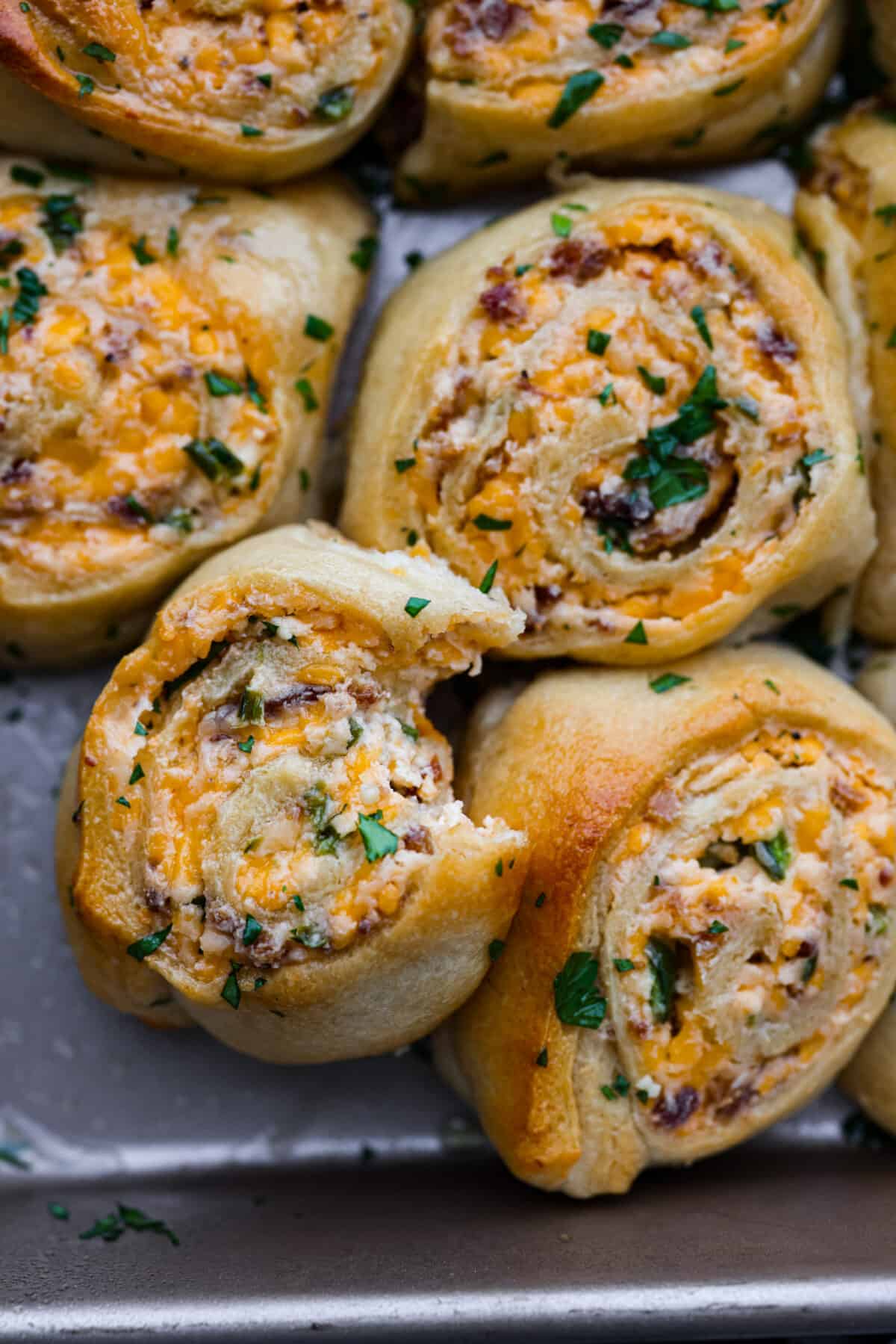 Close view of a roll with a bite out of it. The roll is stacked on top of other jalapeno popper rolls.