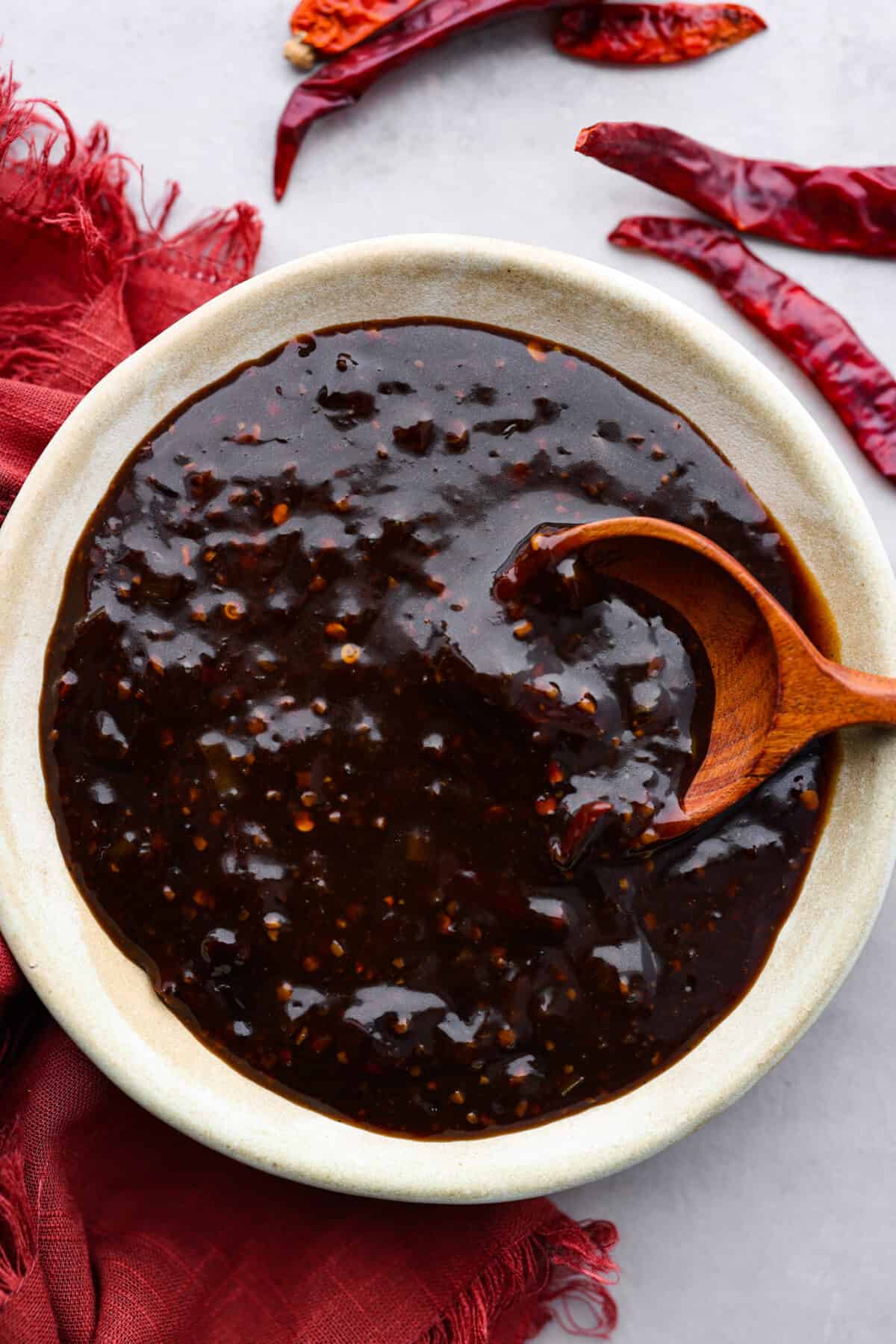 Kung pao sauce in a gray bowl, being stirred with a wooden spoon.