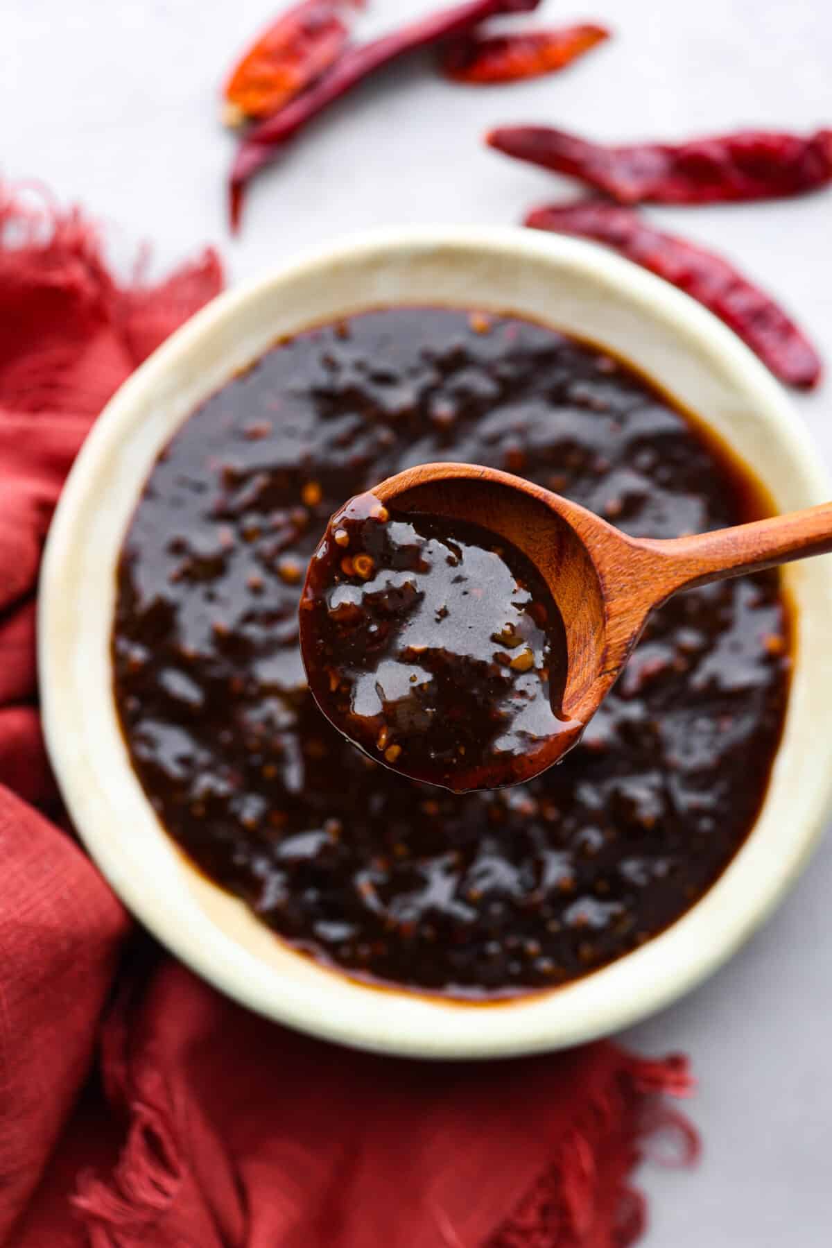 Closeup of sauce in a wooden spoon.