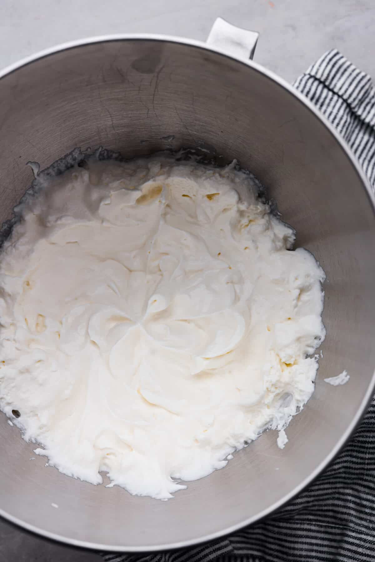 Top-down view of marshmallow whipped cream in a metal mixing bowl.