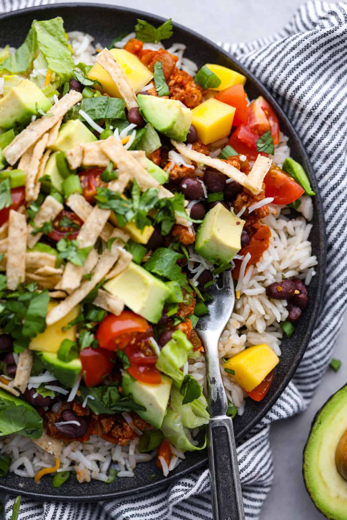 Top-down view of a Mexican haystack on a black plate.