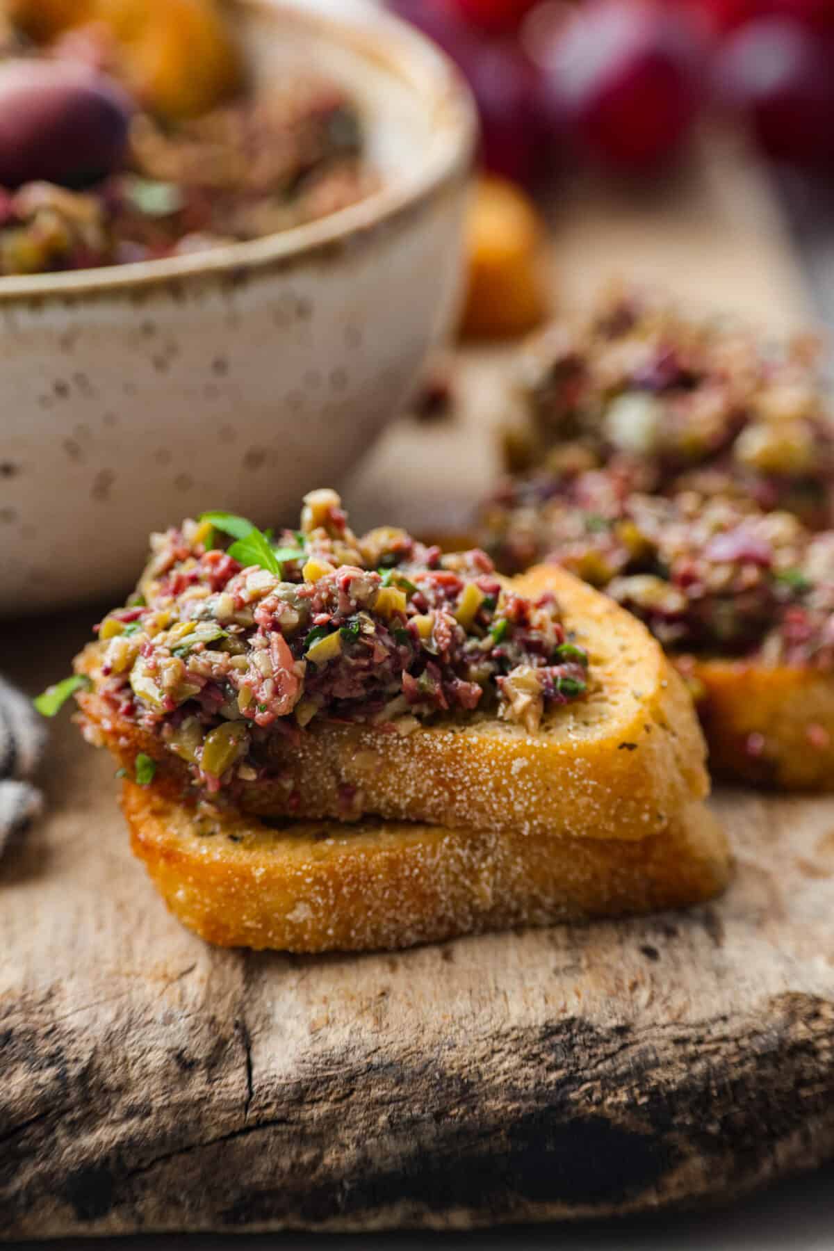 Close view of olive tapenade spread on crostini. 